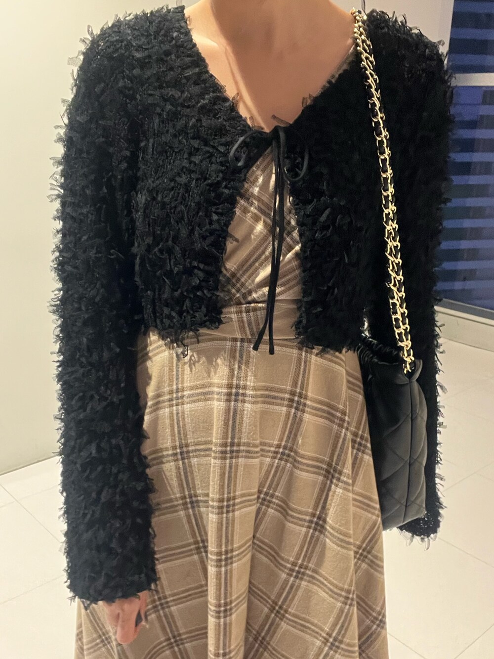 ブラック系のニット/セーター、ブラック系のワンピース、ブラック系のショルダーバッグを着用したレディースの秋コーディネートの4枚目の写真