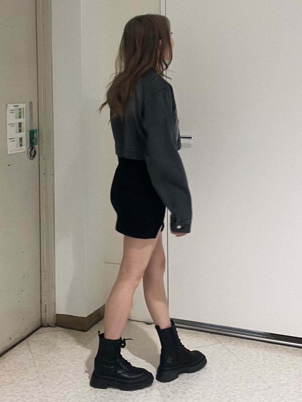 ブルー系のデニムジャケット、ブラック系のワンピース、ブラック系のブーツを着用したレディースの春コーディネートの2枚目の写真