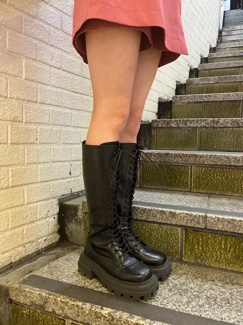 ブラック系のブーツ、ブラック系のショルダーバッグ、ピンク系のワンピースを着用したレディースの冬コーディネートの6枚目の写真