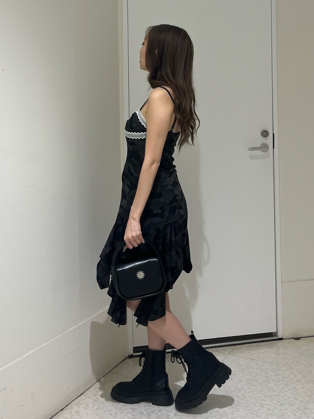 ブラック系のワンピース、ブラック系のハンドバッグ、ブラック系のブーツを着用したレディースの夏コーディネートの2枚目の写真