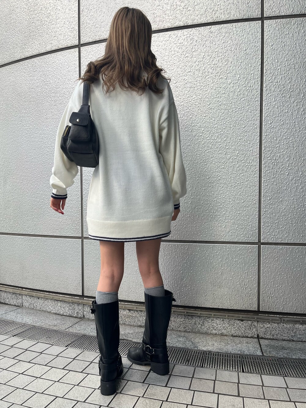 グレー系のハンドバッグ、ブラック系のブーツ、ホワイト系のニット/セーターを着用したレディースの冬コーディネートの3枚目の写真