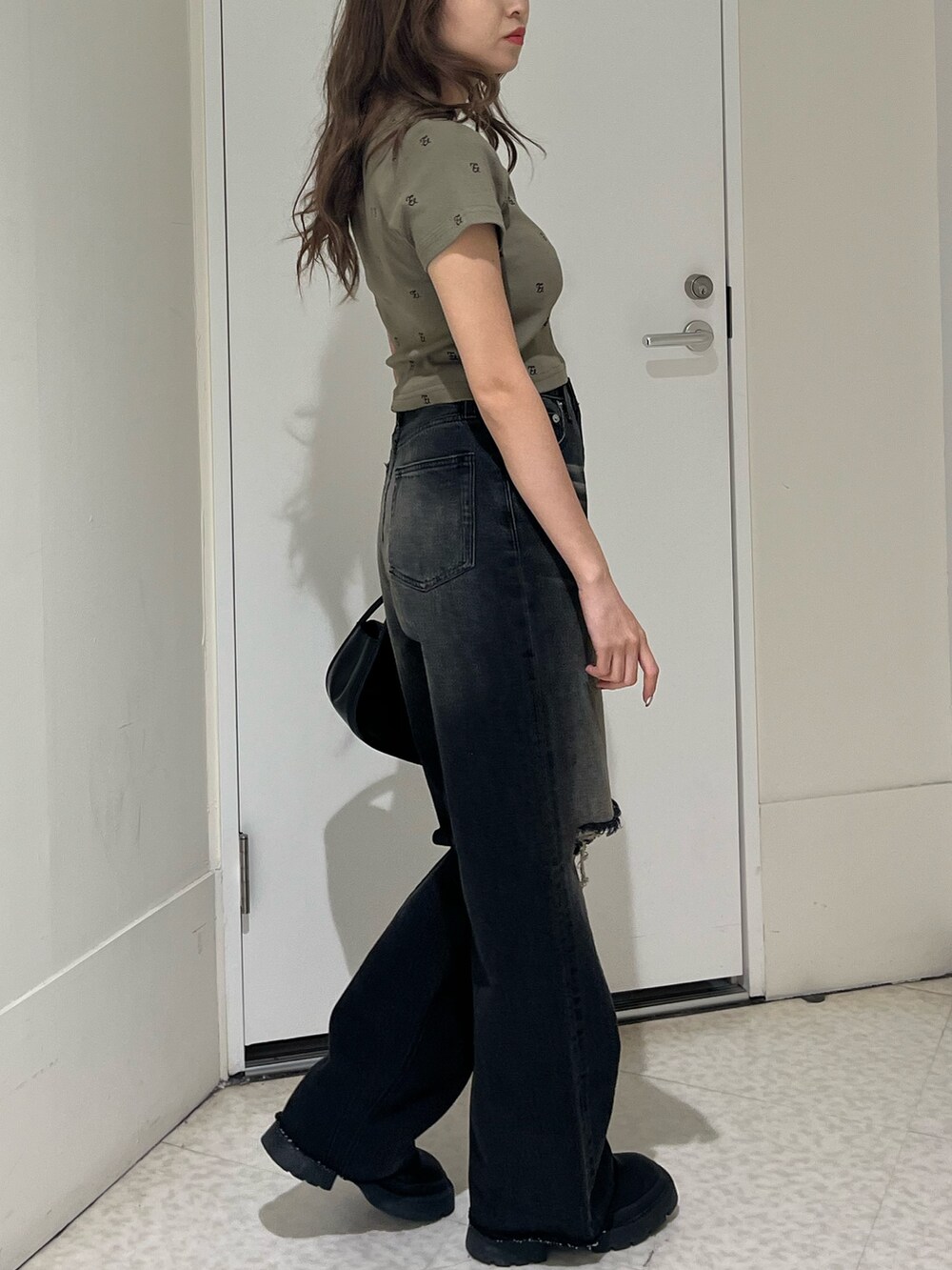 グリーン系のTシャツ/カットソー、ブラック系のブーツ、ブラック系のハンドバッグを着用したレディースの春コーディネートの4枚目の写真