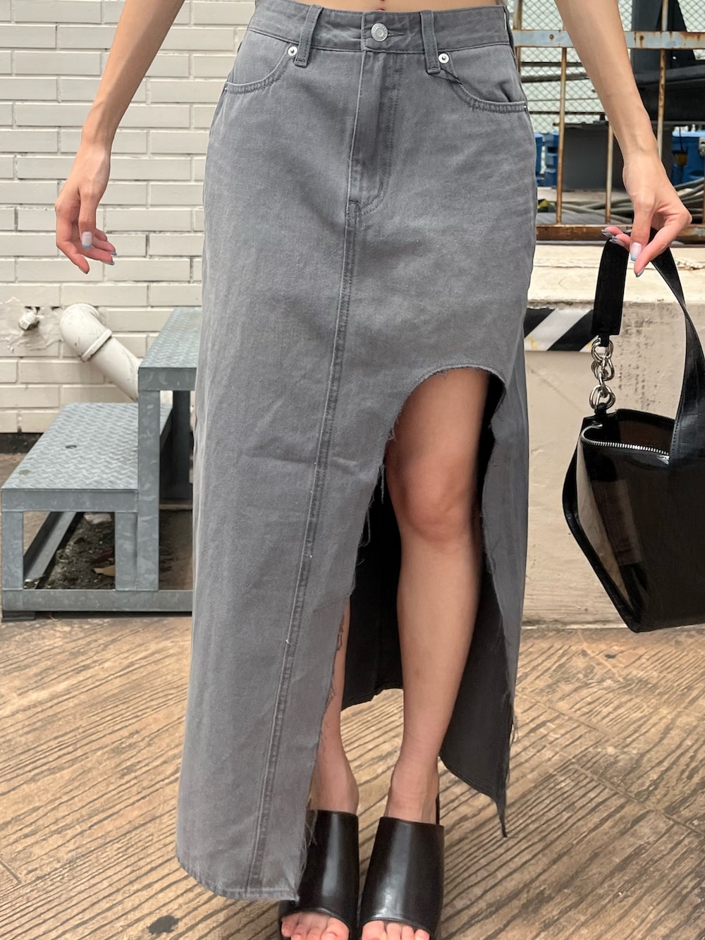 ブラック系のデニムスカート、ブラック系のサンダル、ホワイト系のTシャツ/カットソーを着用したレディースの夏コーディネートの5枚目の写真