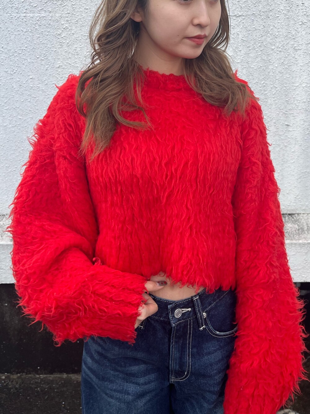 ブラック系のブーツ、レッド系のニット/セーター、ブルー系のデニムパンツを着用したレディースの冬コーディネートの4枚目の写真