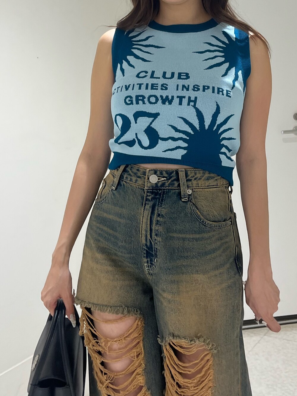 ブラック系のハンドバッグ、ブルー系のデニムパンツ、ブルー系のニット/セーターを着用したレディースの夏コーディネートの5枚目の写真