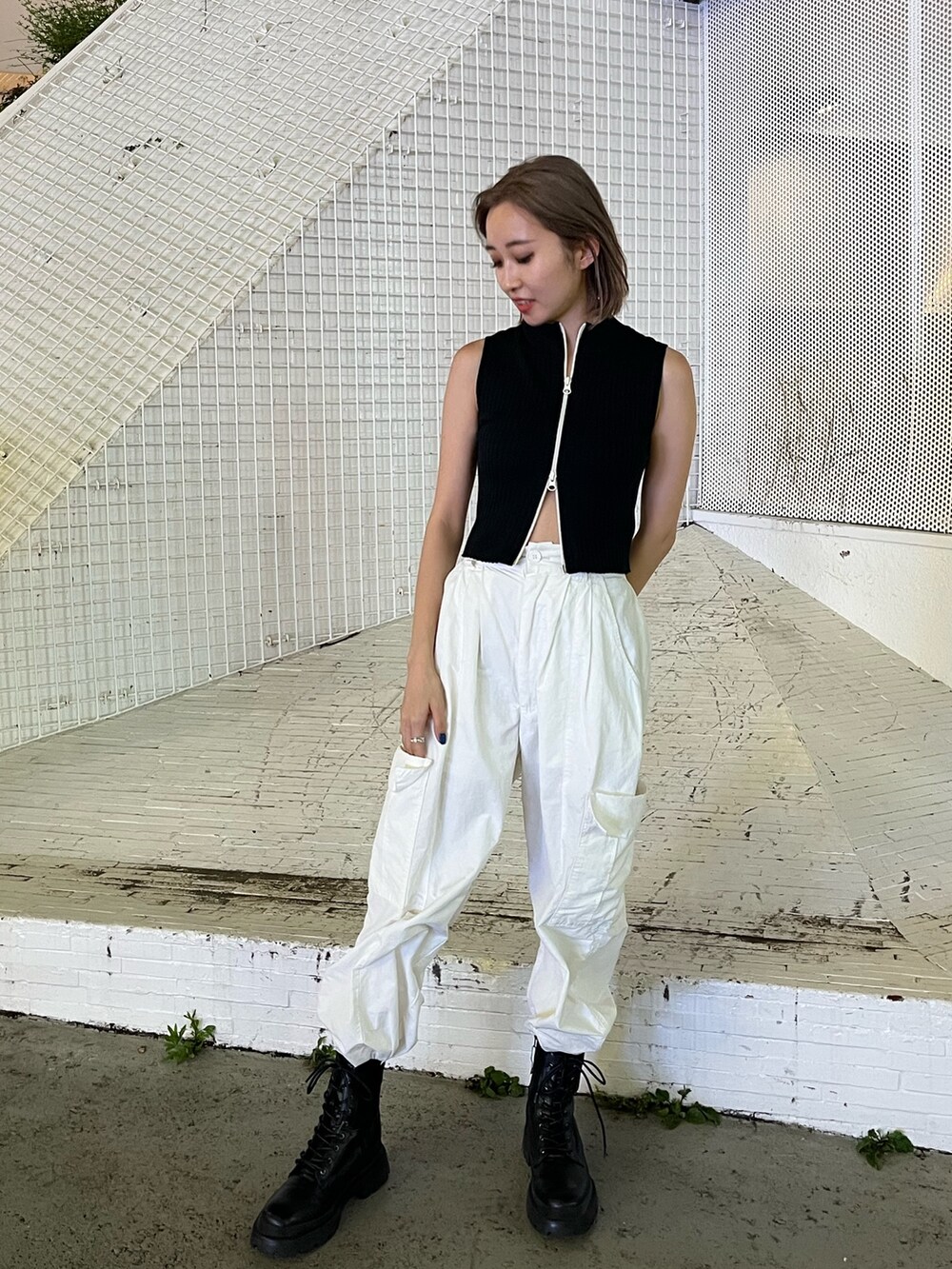 ホワイト系のカーゴパンツ、ブラック系のタンクトップ、ホワイト系のブーツを着用したレディースの夏コーディネートの3枚目の写真