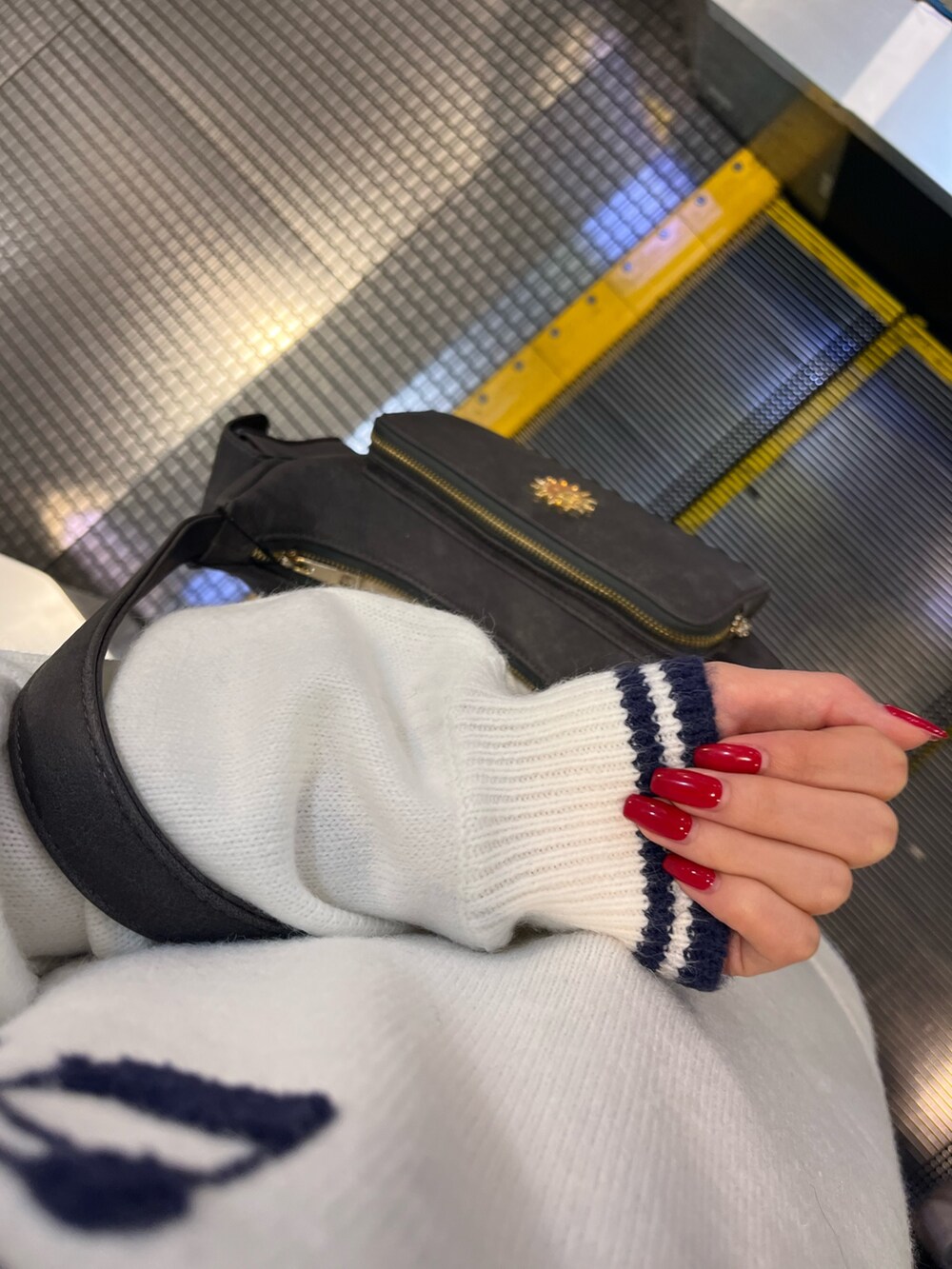 グレー系のハンドバッグ、ブラック系のブーツ、ホワイト系のニット/セーターを着用したレディースの冬コーディネートの7枚目の写真