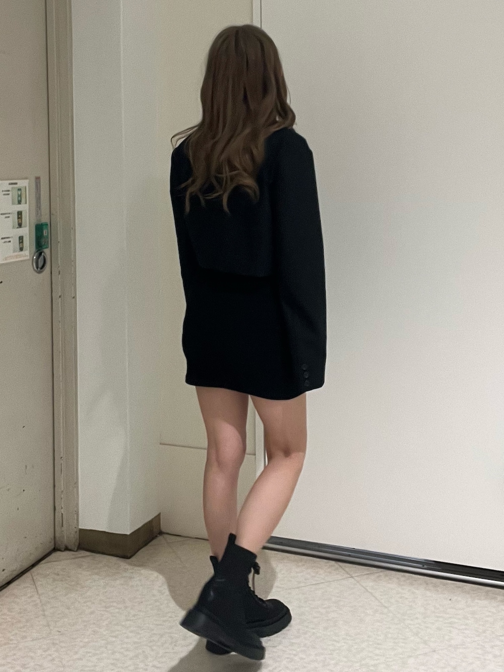 ブラック系のテーラードジャケット、ブラック系のワンピース、ブラック系のブーツを着用したレディースの春コーディネートの3枚目の写真