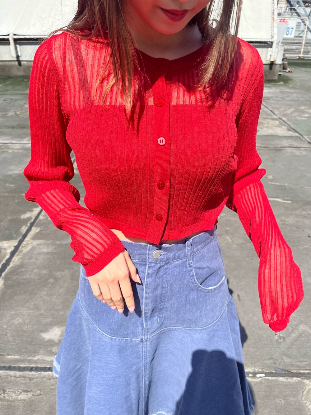 レッド系のニット/セーター、シルバー系のパンプス、ブルー系のデニムスカートを着用したレディースの春コーディネートの6枚目の写真