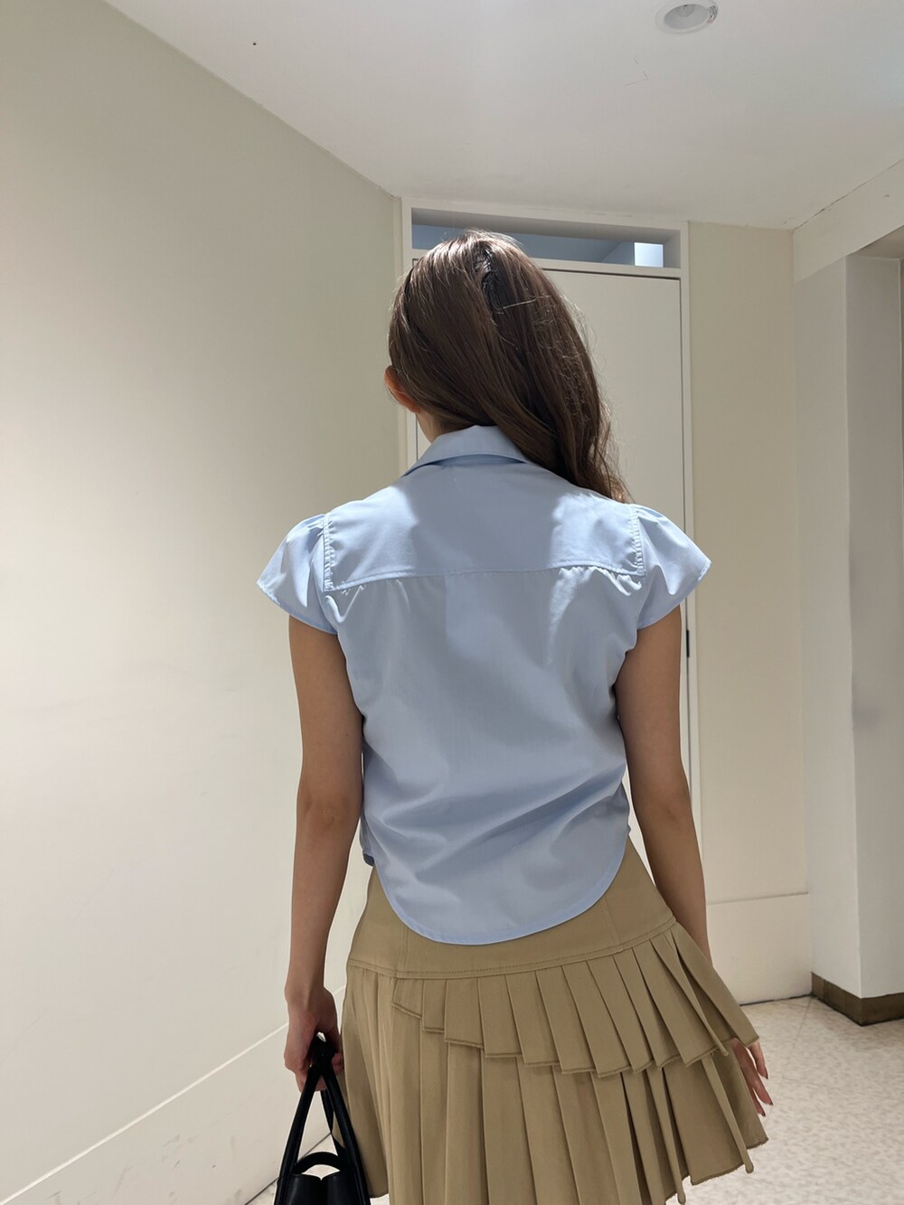 ブルー系のシャツ/ブラウス、ベージュ系のスカート、ブラック系のブーツを着用したレディースの春コーディネートの6枚目の写真
