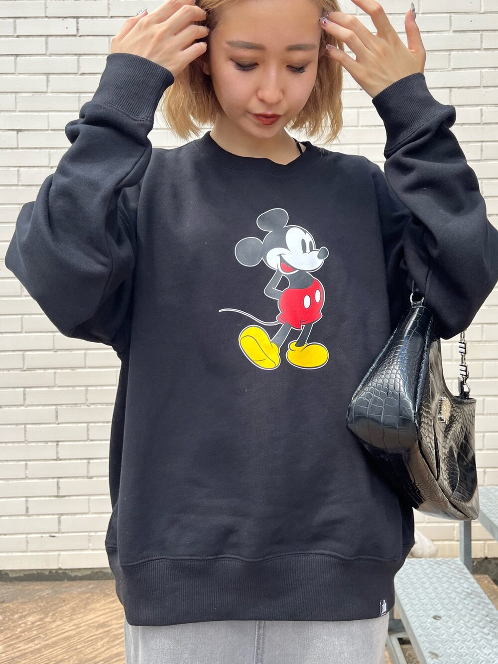 ブラック系のデニムスカート、ホワイト系のブーツ、ブラック系のハンドバッグを着用したレディースの夏コーディネートの6枚目の写真