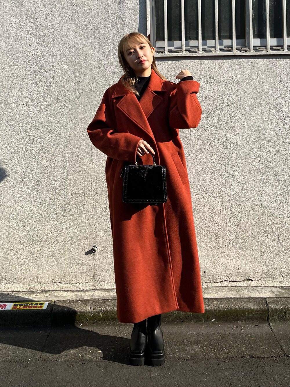 ブラック系のワンピース、オレンジ系のその他アウター、ブラック系のショルダーバッグを着用したレディースの冬コーディネートの2枚目の写真