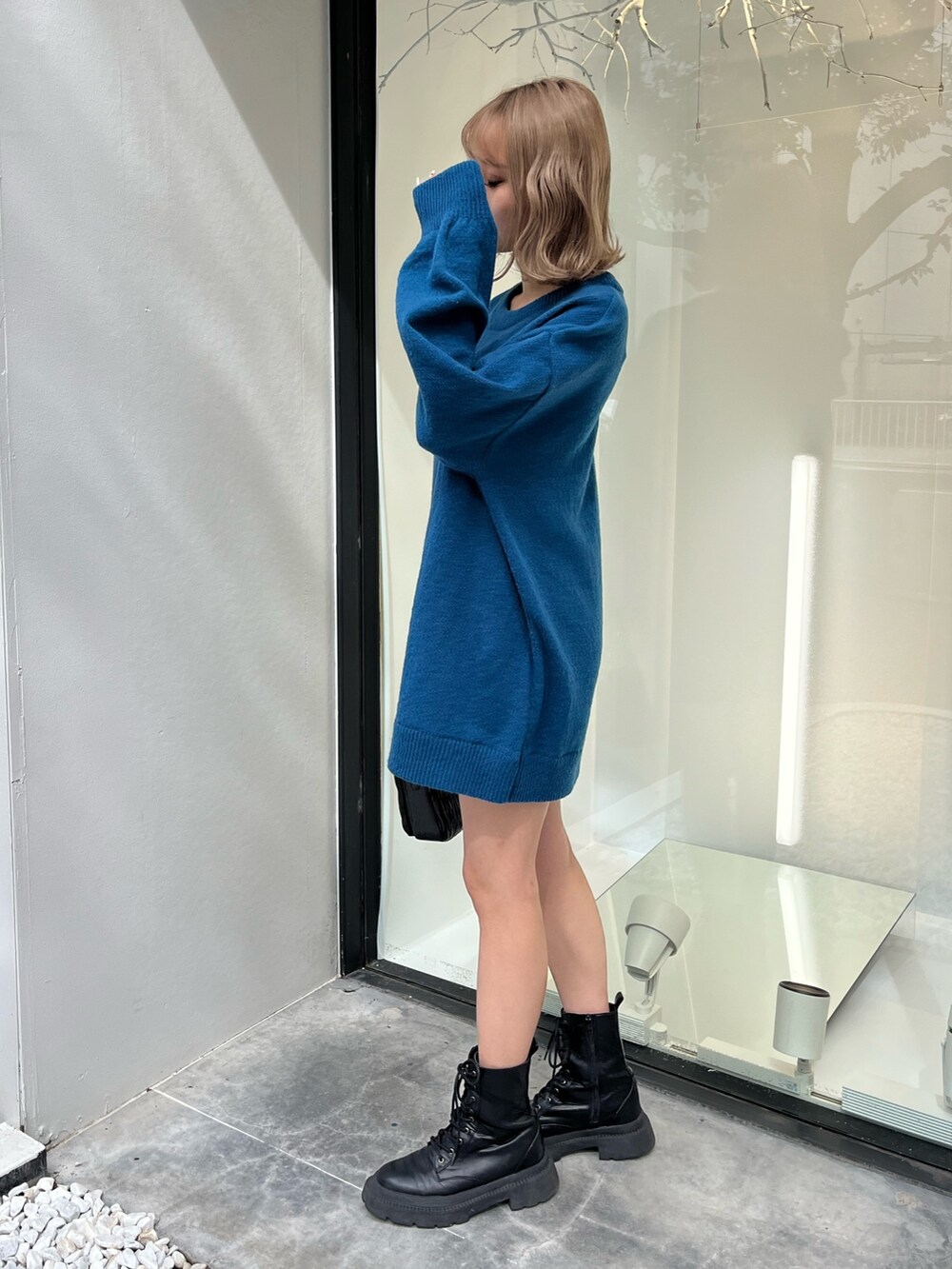 シルバー系のショルダーバッグ、ホワイト系のブーツ、ブルー系のニット/セーターを着用したレディースの秋コーディネートの2枚目の写真