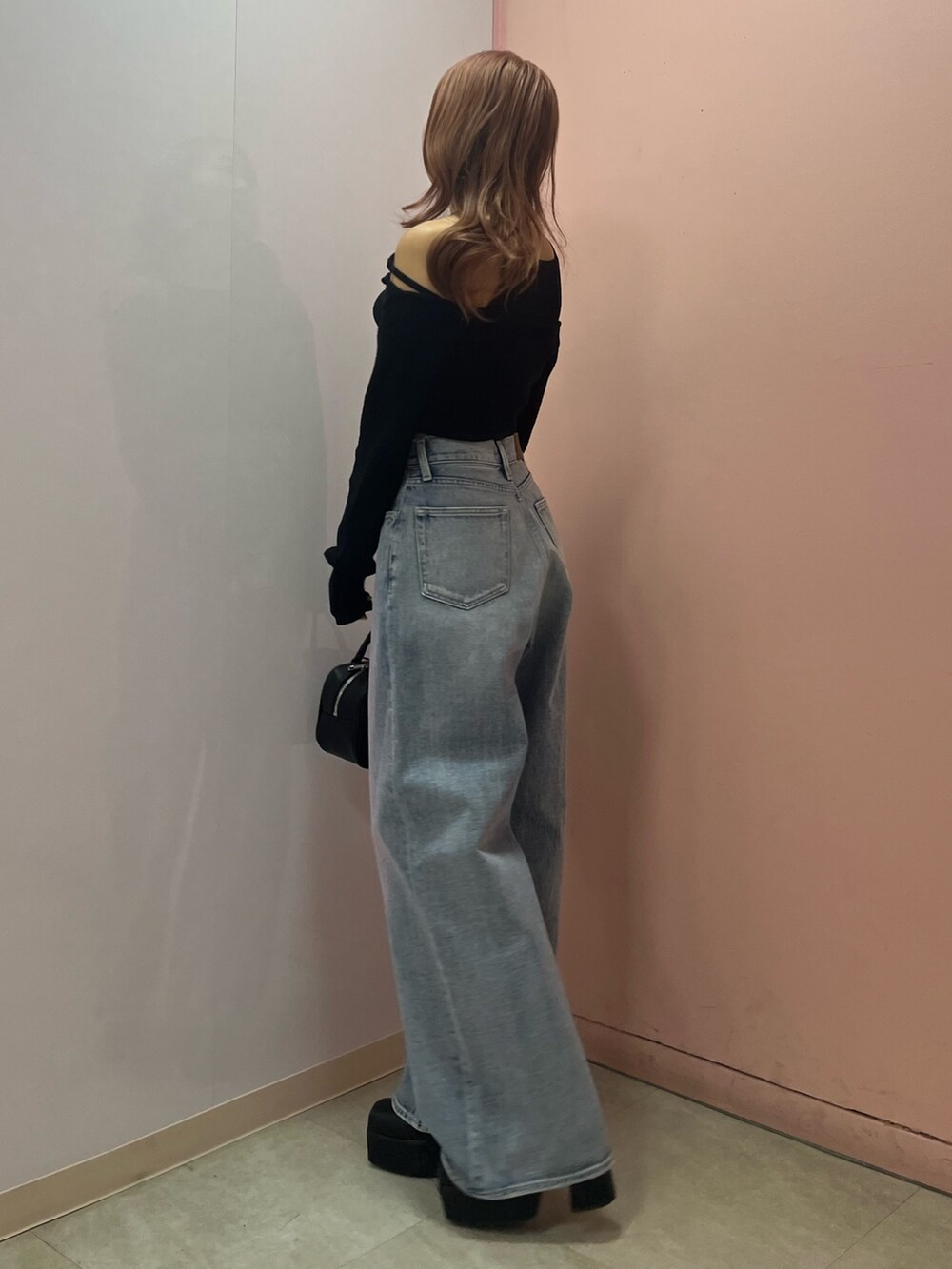 ブラック系のボストンバッグ、ブラック系のブーツ、イエロー系のニット/セーターを着用したレディースの春コーディネートの3枚目の写真