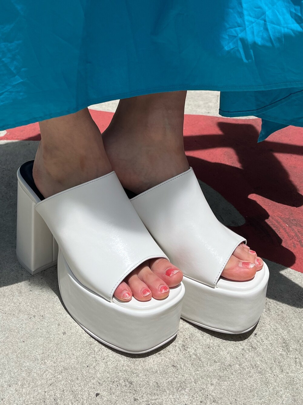 ブラック系のデニムスカート、ブラック系のサンダル、ホワイト系のTシャツ/カットソーを着用したレディースの夏コーディネートの8枚目の写真