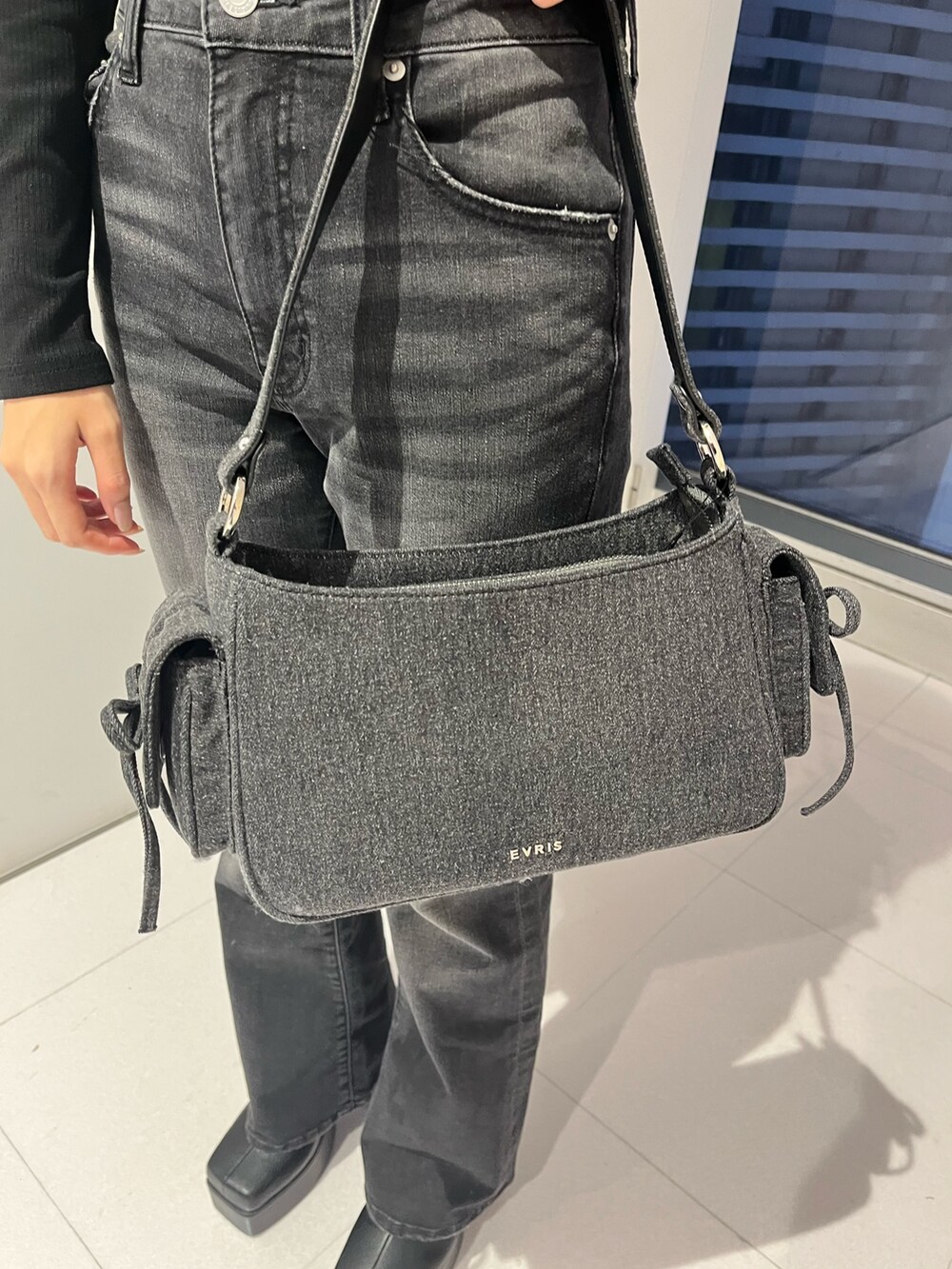 ブラック系のデニムパンツ、ブラック系のハンドバッグ、ブラック系のブーツを着用したレディースの秋コーディネートの3枚目の写真