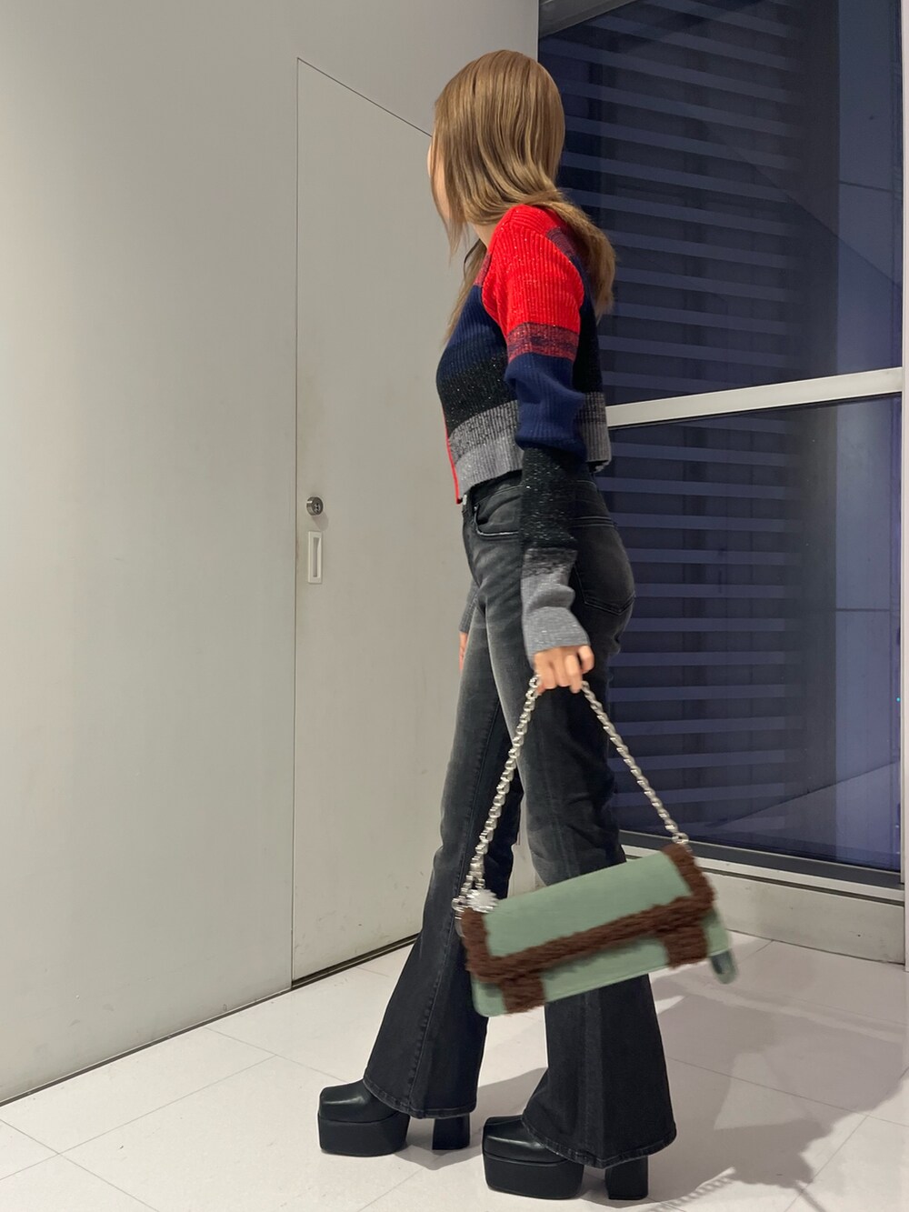 レッド系のニット/セーター、ブラック系のデニムパンツ、ブルー系のショルダーバッグを着用したレディースの秋コーディネートの2枚目の写真