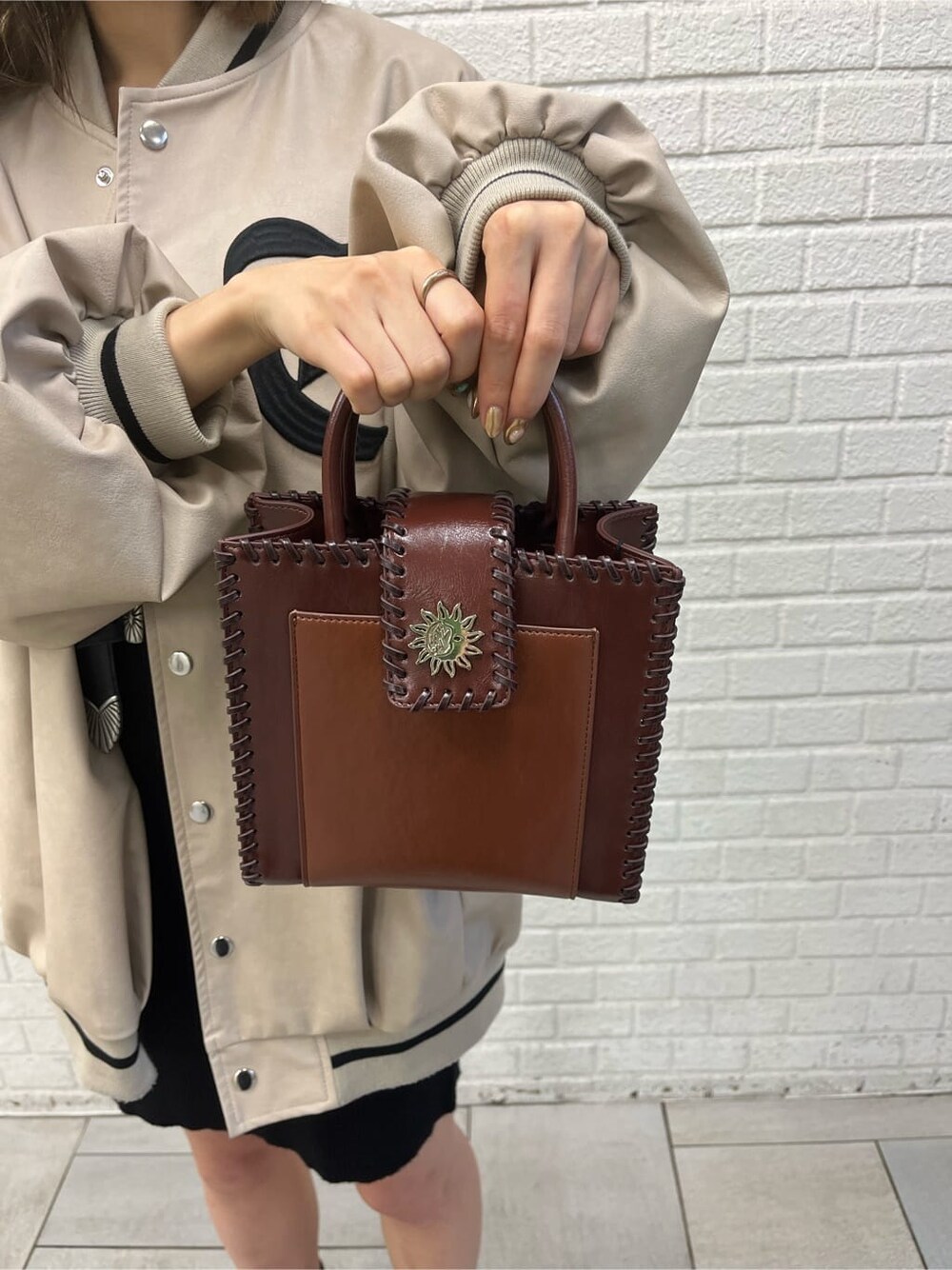 ブラック系のワンピース、ブラック系のブーツ、ベージュ系のブルゾンを着用したレディースの秋コーディネートの3枚目の写真