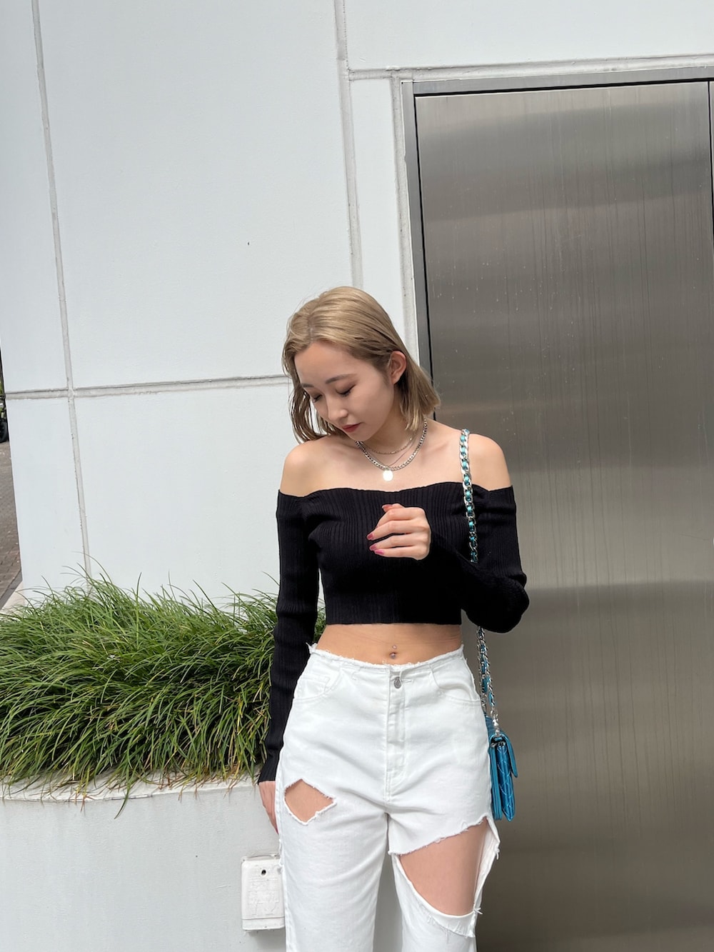 グリーン系のニット/セーター、ブラック系のデニムパンツ、ブラック系のショルダーバッグを着用したレディースの春コーディネートの8枚目の写真