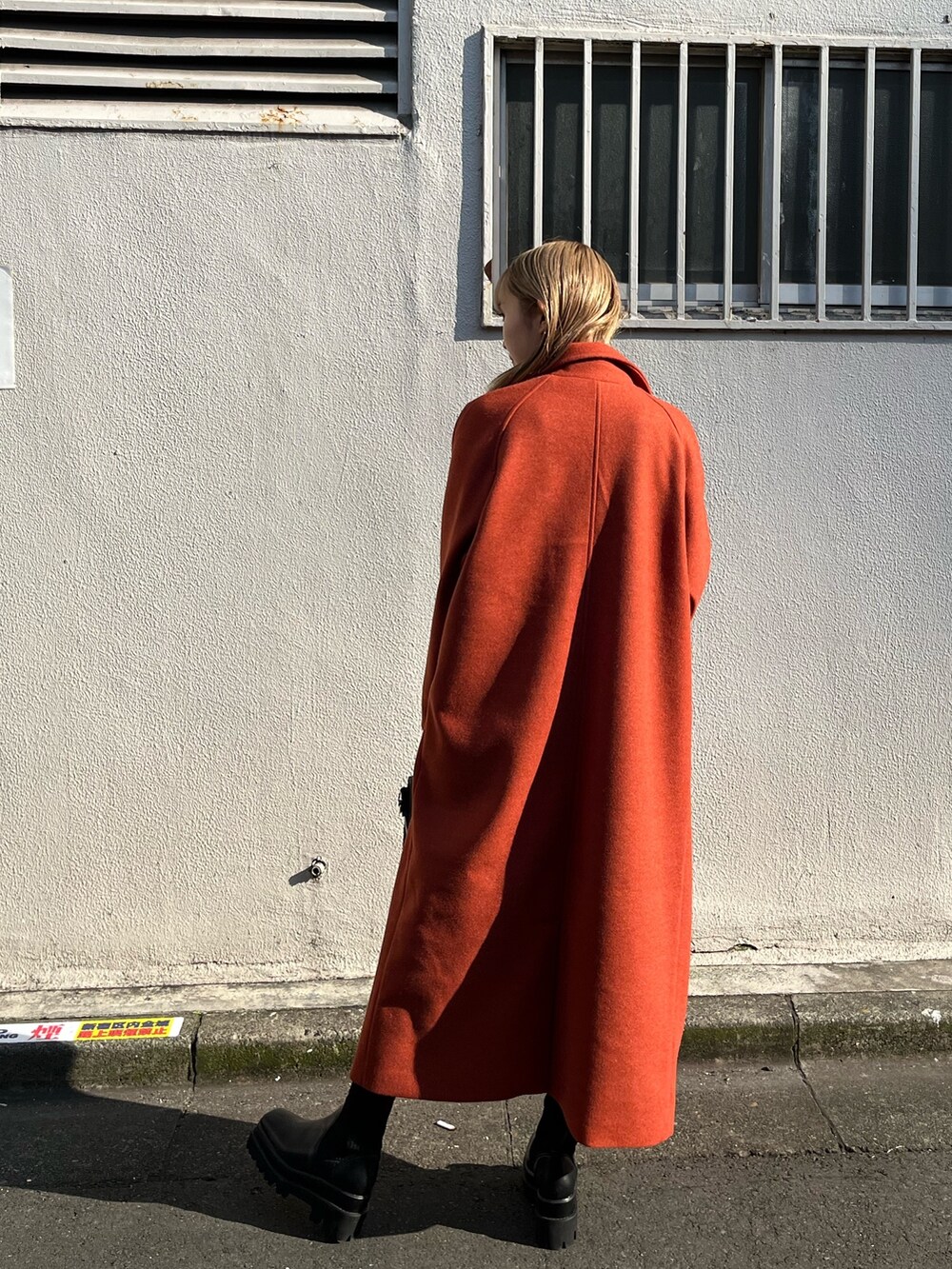 ブラック系のワンピース、オレンジ系のその他アウター、ブラック系のショルダーバッグを着用したレディースの冬コーディネートの4枚目の写真