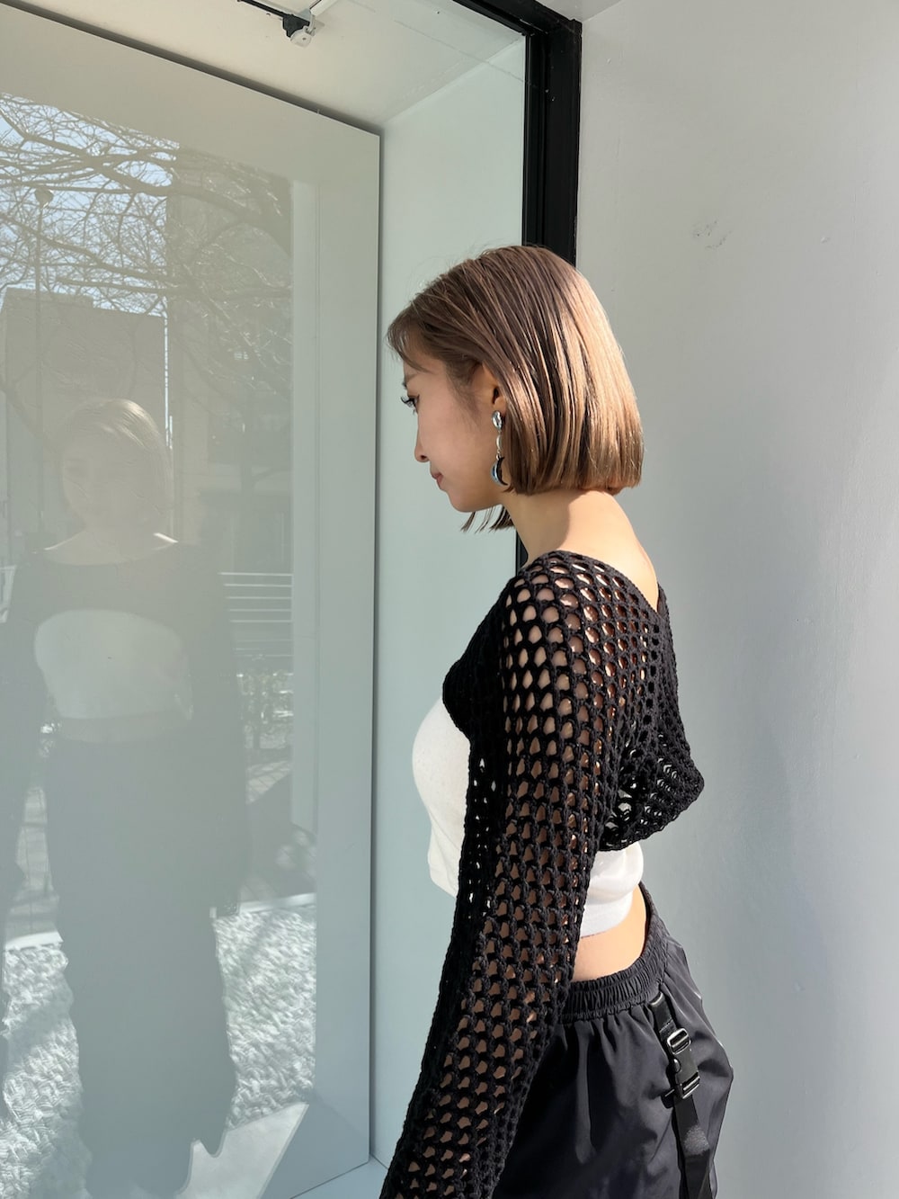 ブラック系のスカート、ブラック系のニット/セーター、パープル系のハンドバッグを着用したレディースの春コーディネートの4枚目の写真