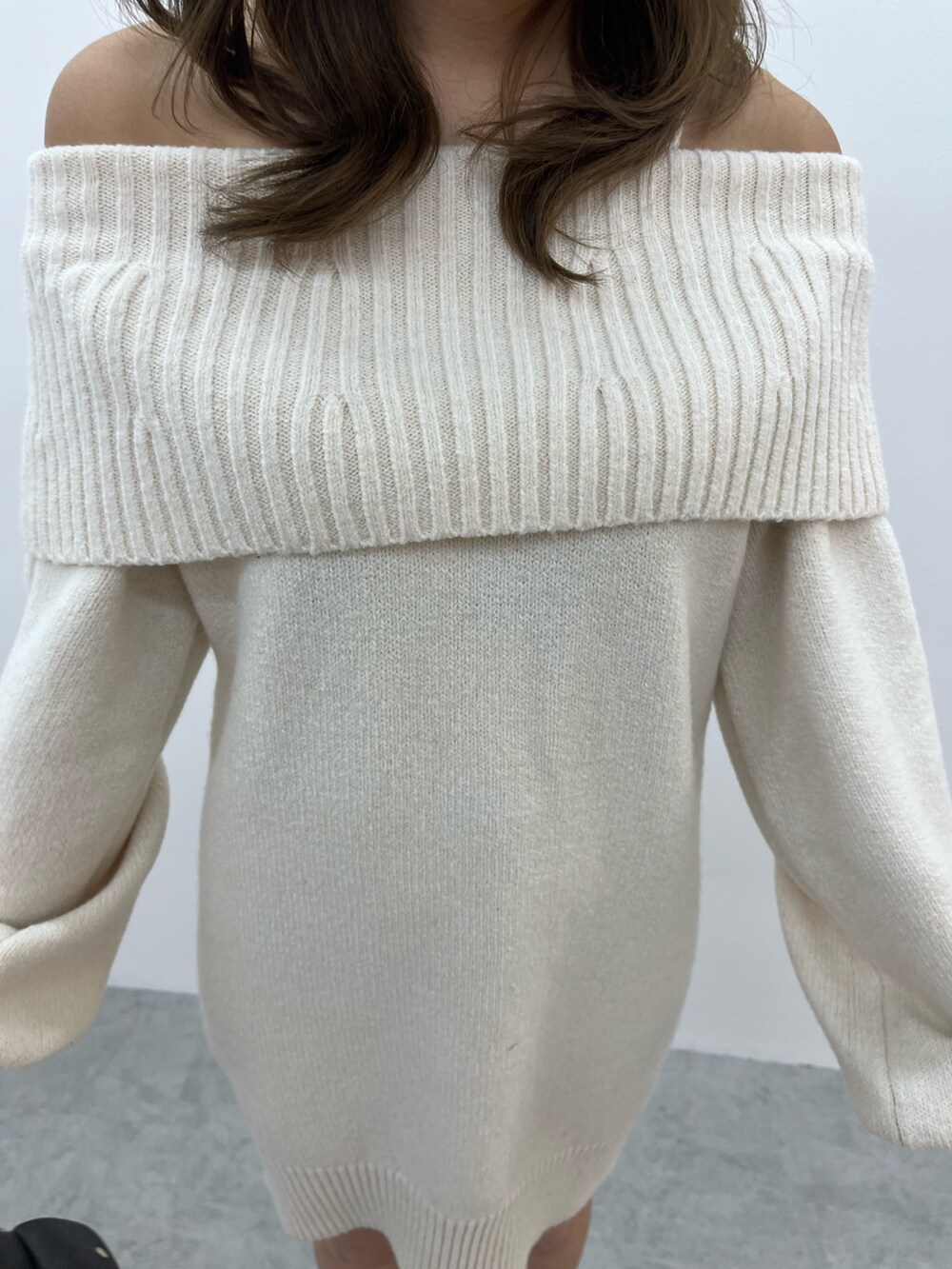 グレー系のハンドバッグ、ホワイト系のワンピース、ブラック系のブーツを着用したレディースの冬コーディネートの5枚目の写真