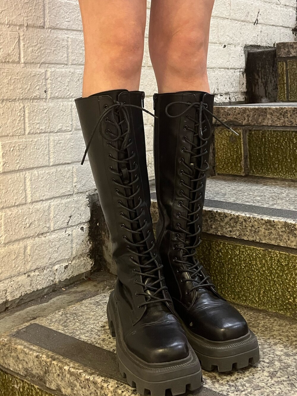 ブラック系のブーツ、ブラック系のショルダーバッグ、ピンク系のワンピースを着用したレディースの冬コーディネートの8枚目の写真