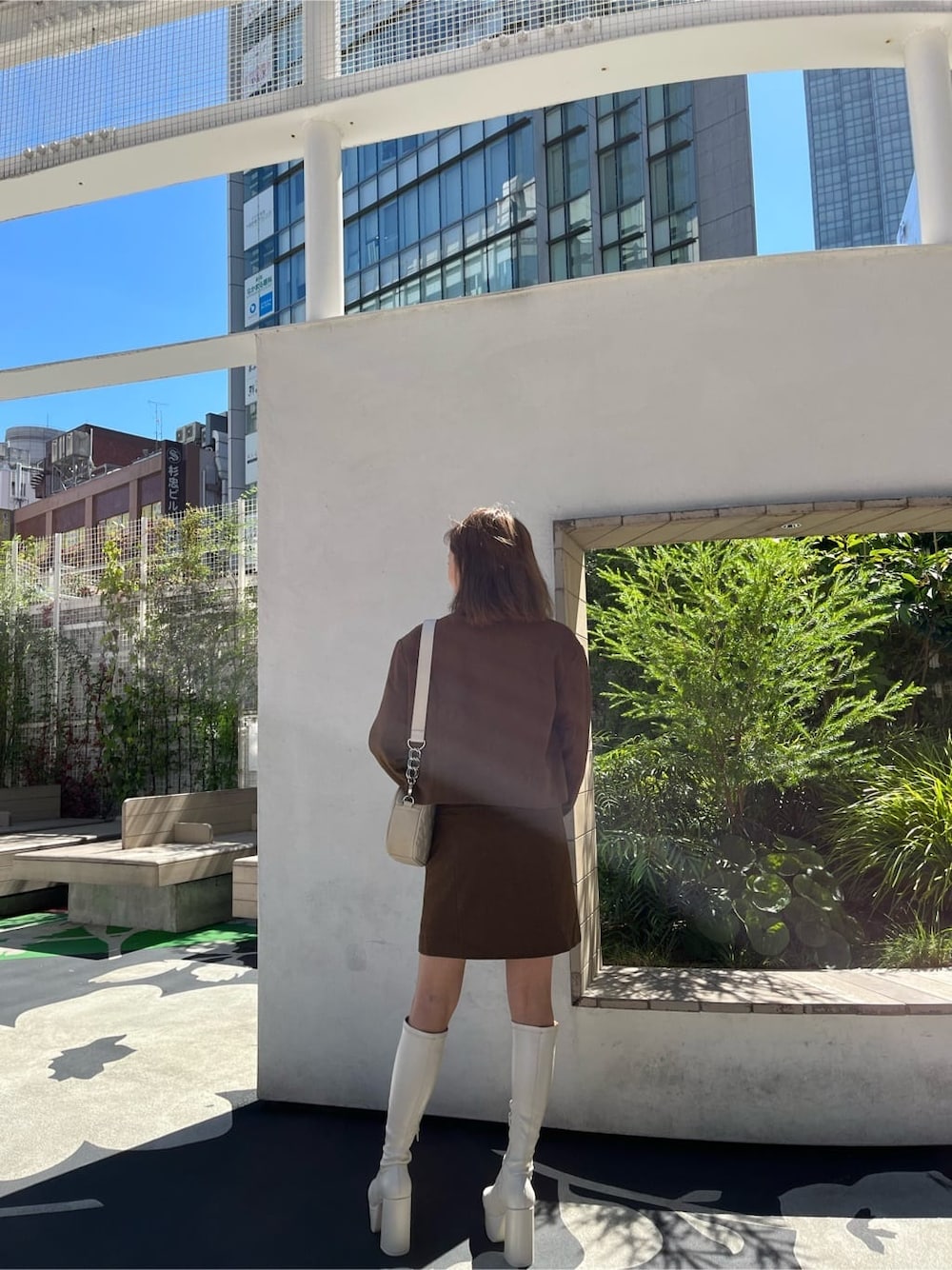 ブラウン系のスカート、ブラック系のニット/セーター、ブラック系のブーツを着用したレディースの秋コーディネートの3枚目の写真