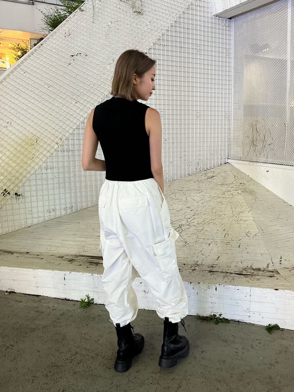 ホワイト系のカーゴパンツ、ブラック系のタンクトップ、ホワイト系のブーツを着用したレディースの夏コーディネートの6枚目の写真