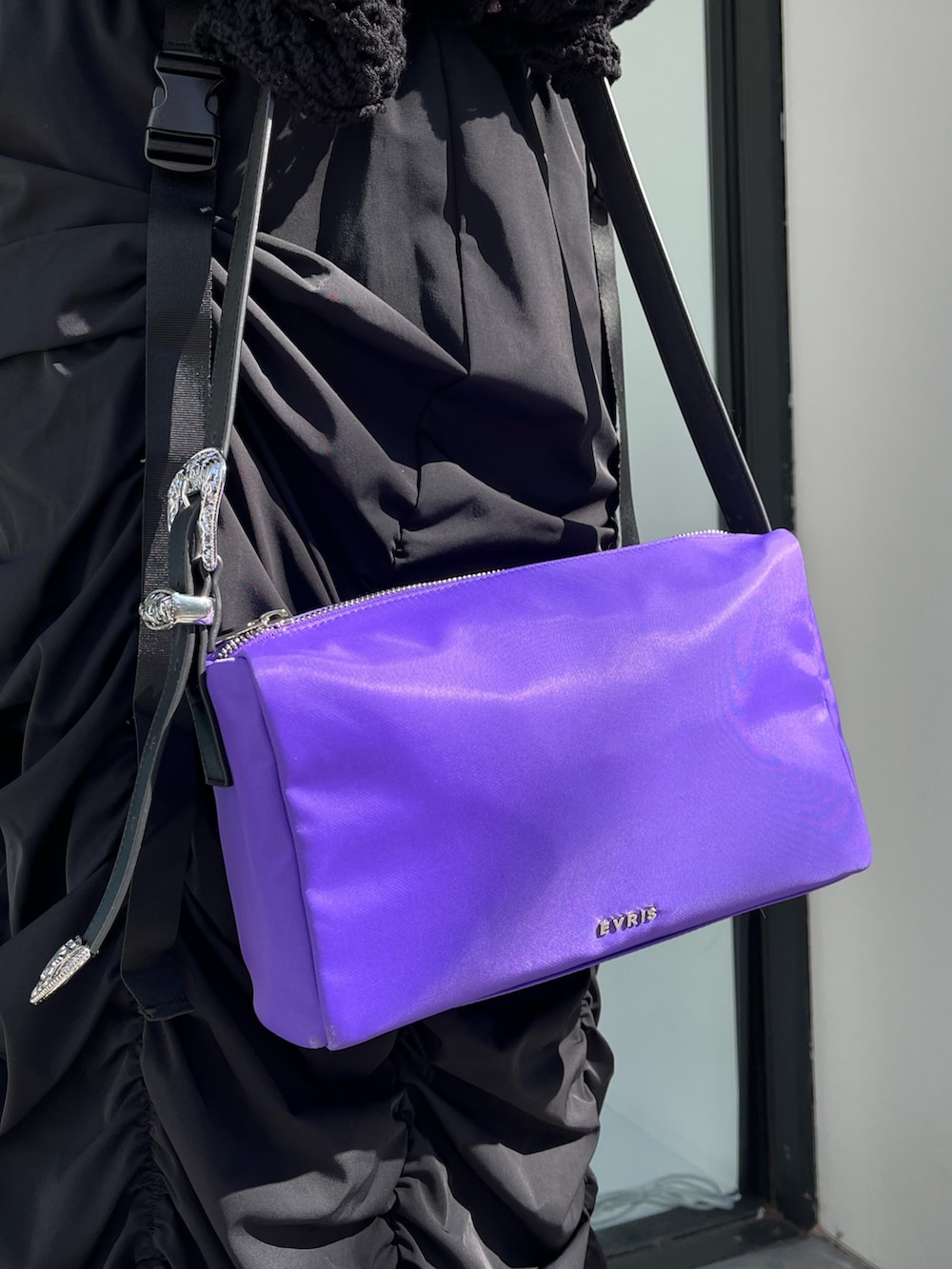 ブラック系のスカート、ブラック系のニット/セーター、パープル系のハンドバッグを着用したレディースの春コーディネートの5枚目の写真