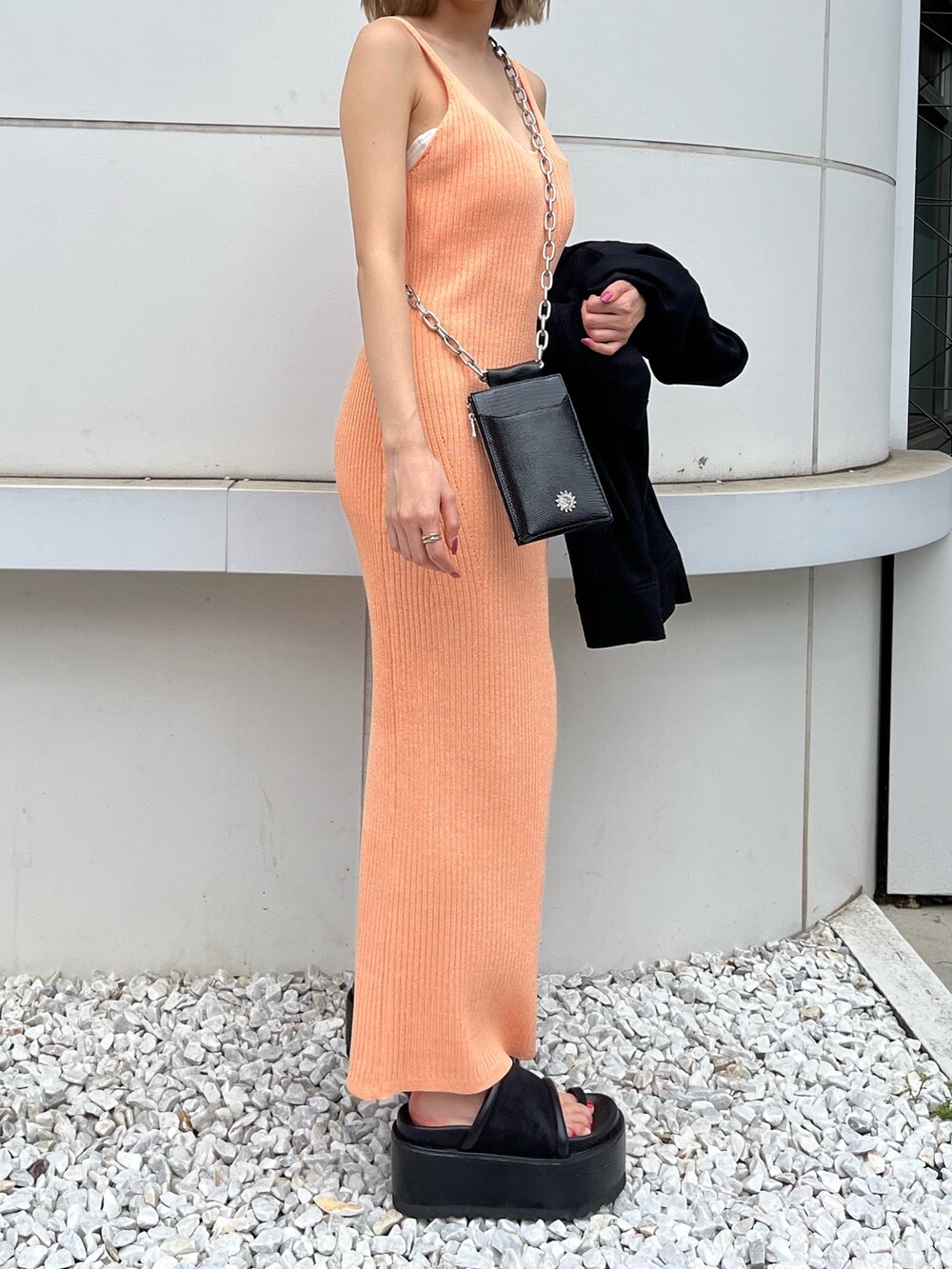 ブラック系のサンダル、ブラック系のミリタリージャケット、オレンジ系のワンピースを着用したレディースの春コーディネートの3枚目の写真