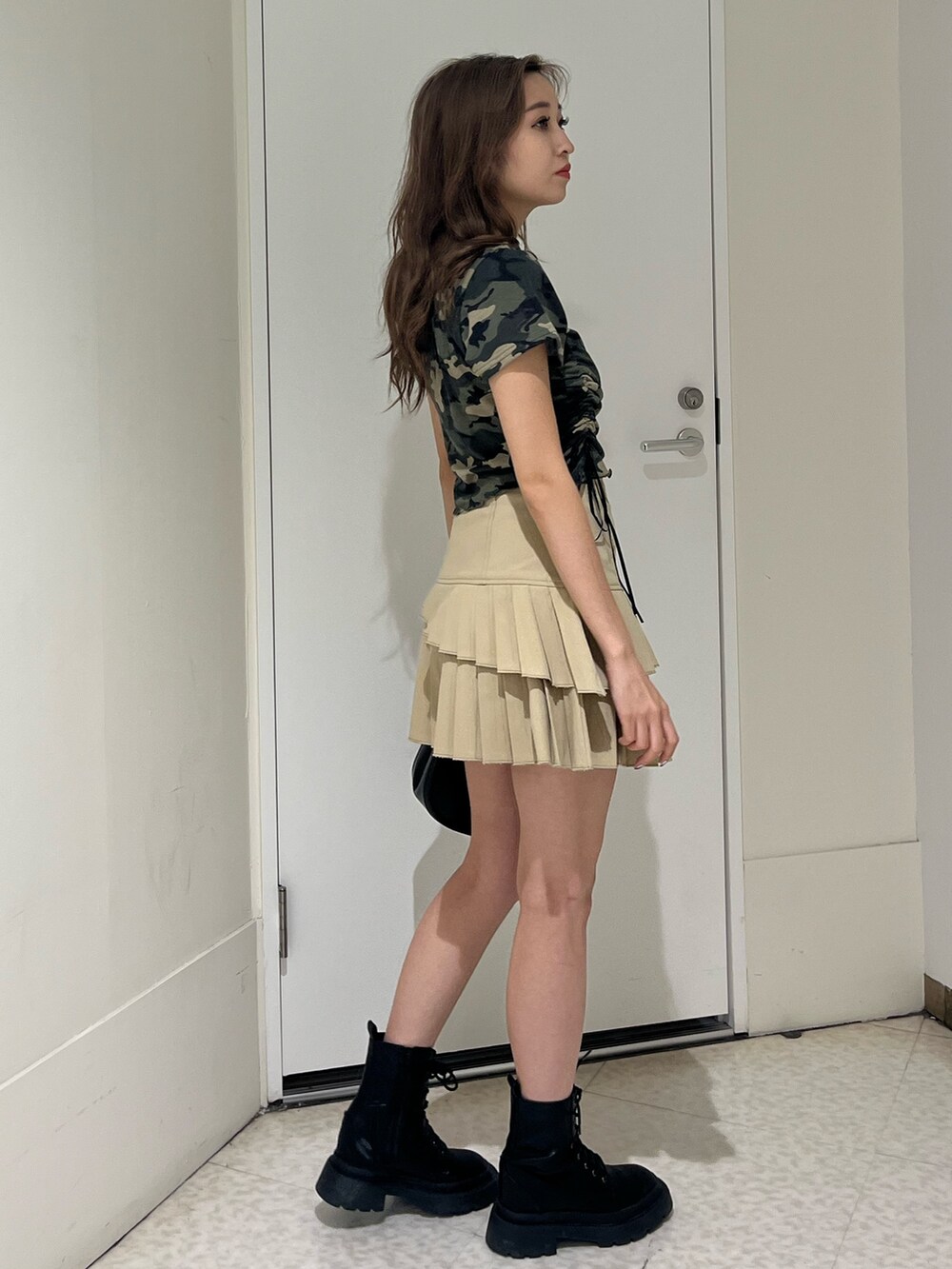 グリーン系のTシャツ/カットソー、ブラック系のブーツ、ベージュ系のスカートを着用したレディースの春コーディネートの4枚目の写真