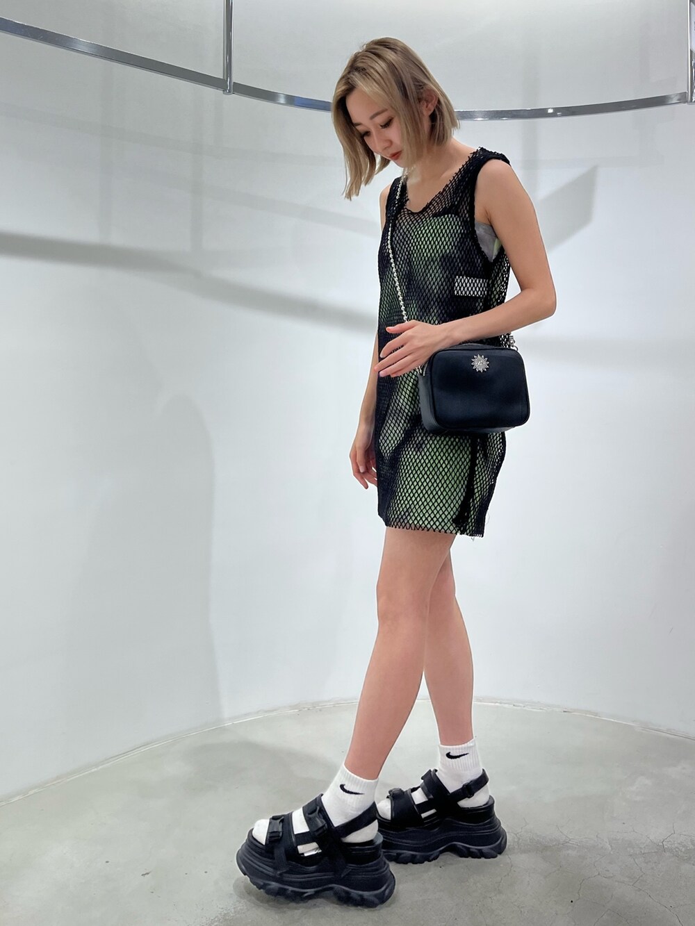 グリーン系のワンピース、ブラック系のサンダル、ブラック系のショルダーバッグを着用したレディースの春コーディネートの2枚目の写真