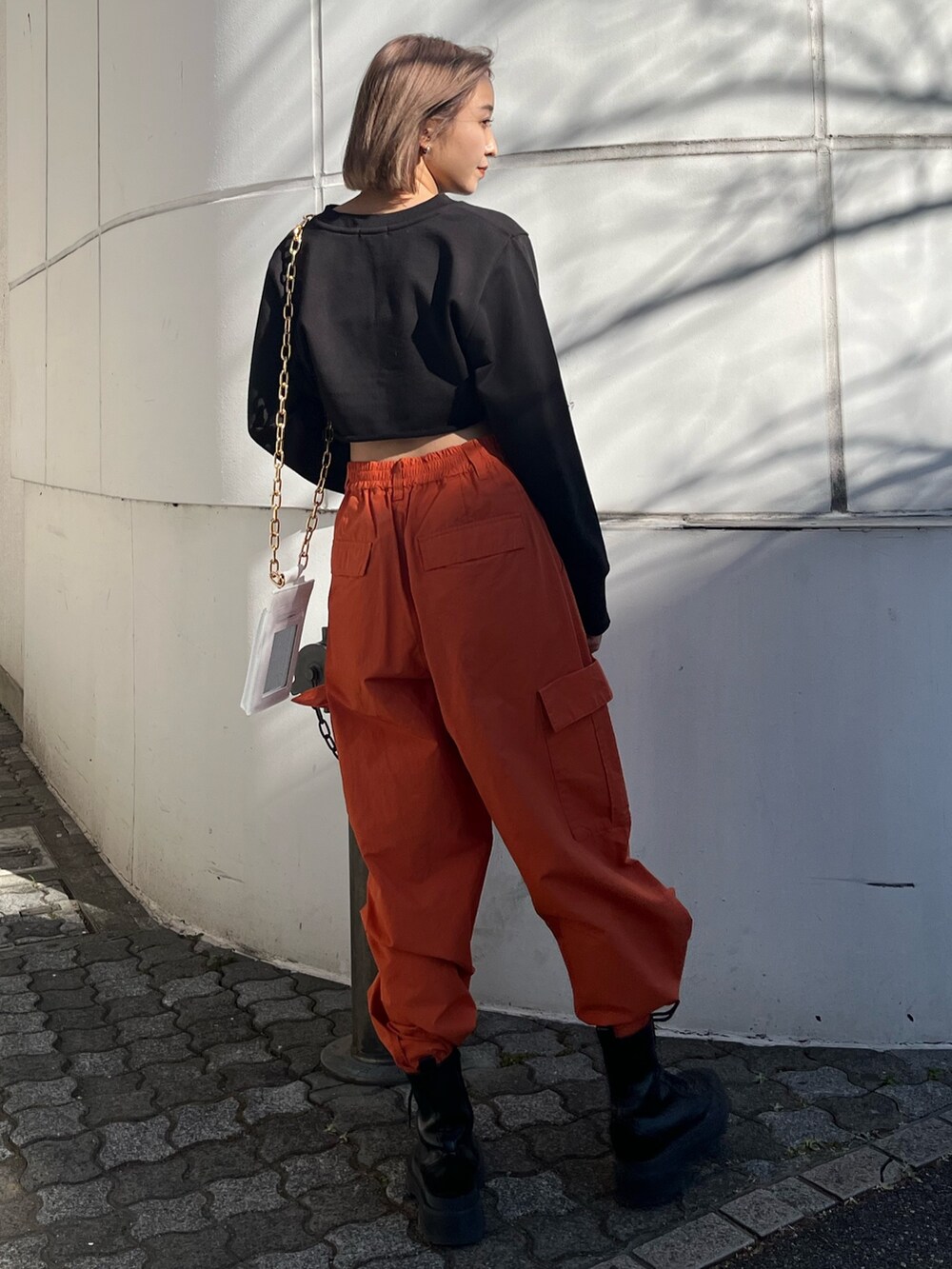 オレンジ系のカーゴパンツ、ホワイト系のブーツ、ブラック系のTシャツ/カットソーを着用したレディースの冬コーディネートの6枚目の写真