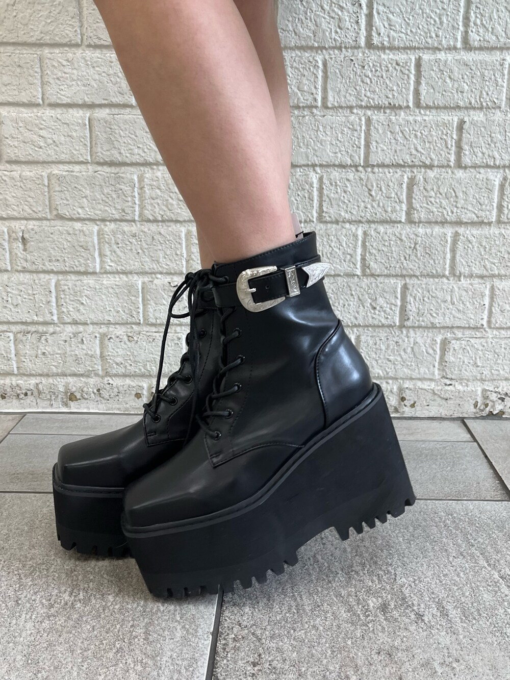 ホワイト系のパーカー、パープル系のスタジャン、ブラック系のブーツを着用したレディースの冬コーディネートの9枚目の写真