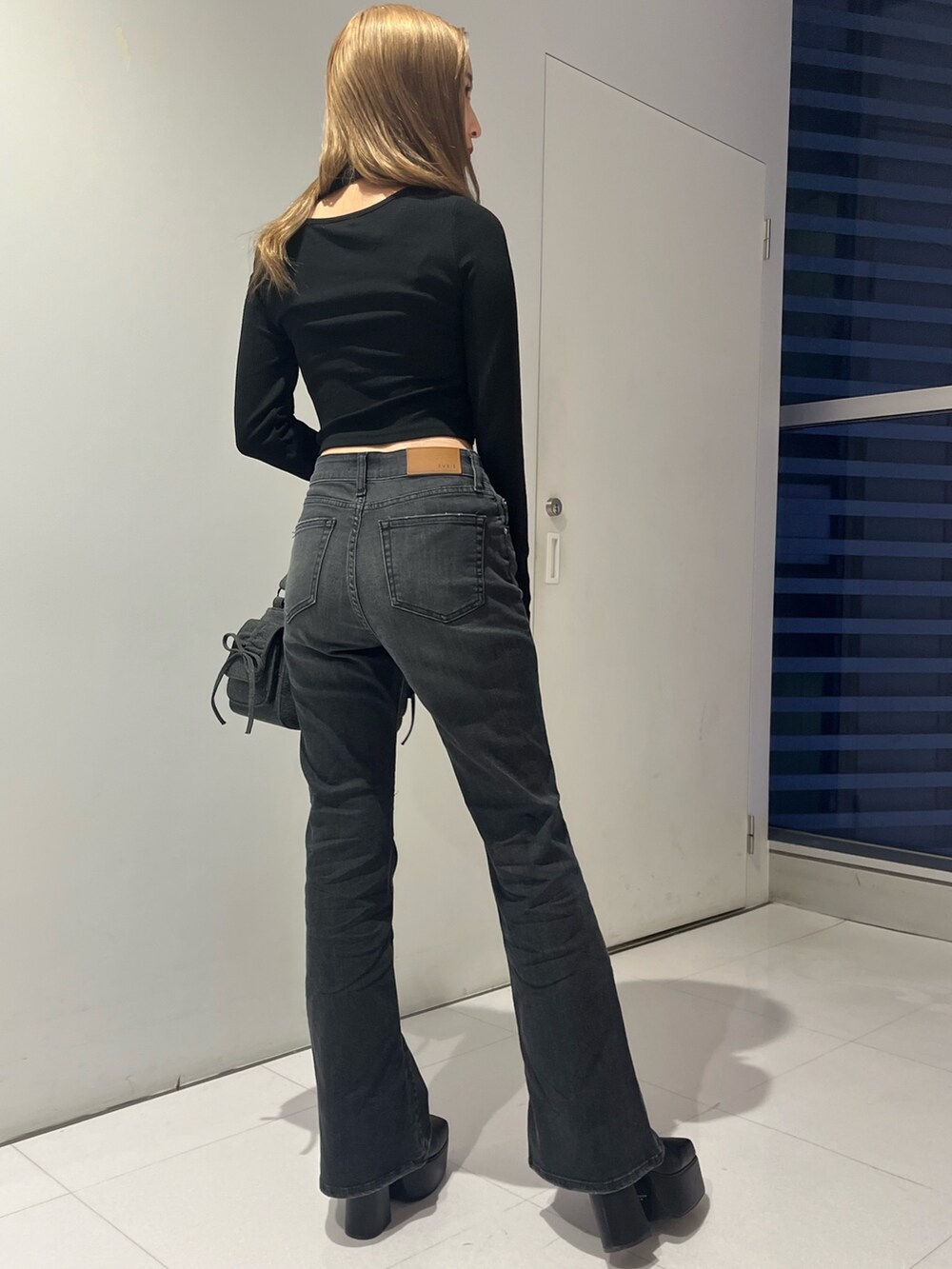 ブラック系のデニムパンツ、ブラック系のハンドバッグ、ブラック系のブーツを着用したレディースの秋コーディネートの6枚目の写真