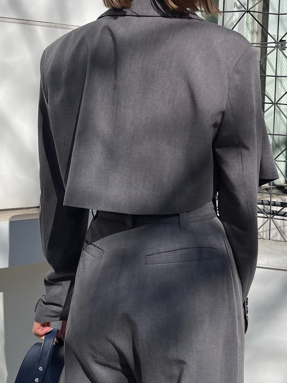 グレー系のテーラードジャケット、グレー系のその他パンツ、ブラック系のショルダーバッグを着用したレディースの春コーディネートの6枚目の写真