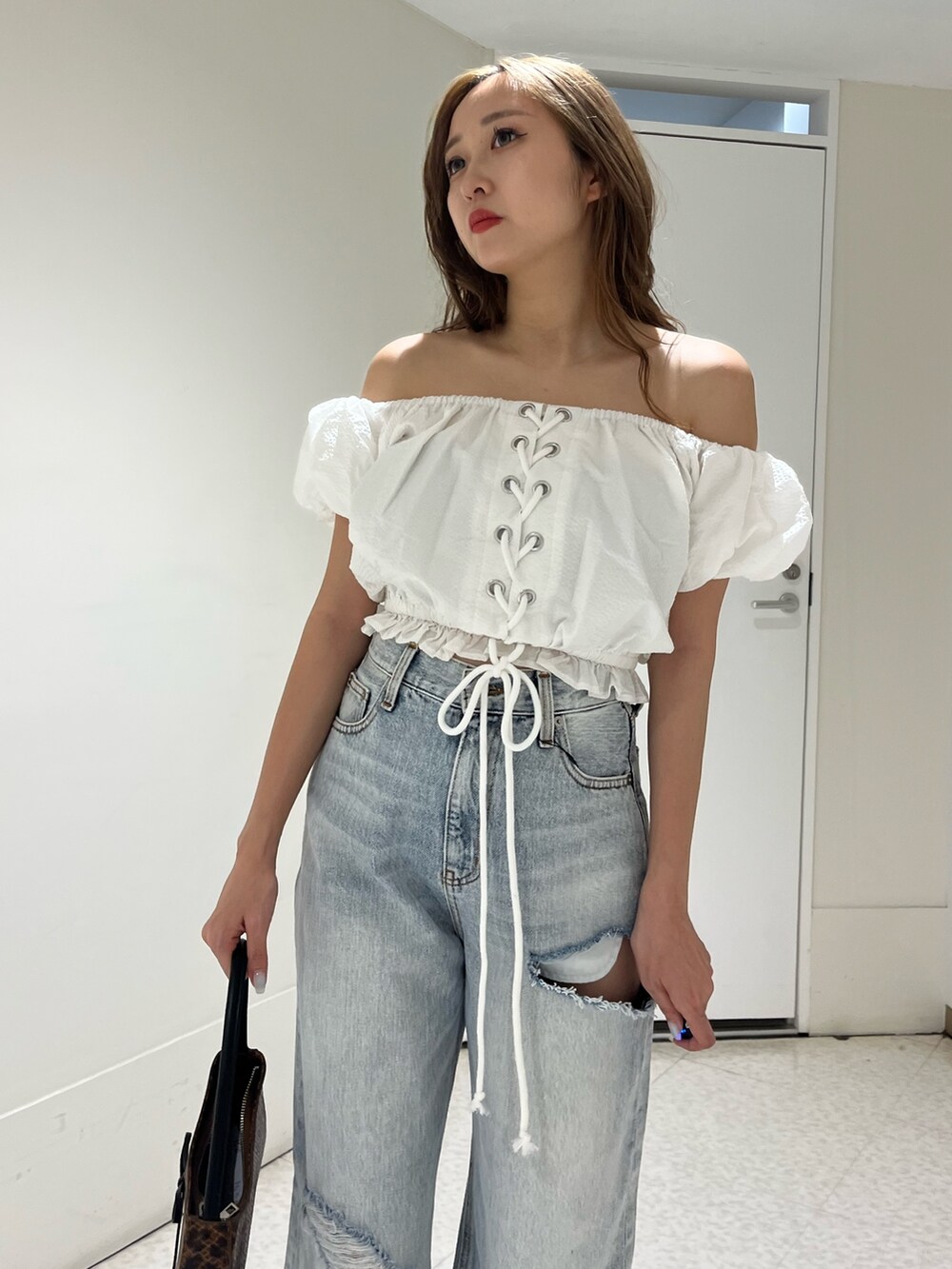 ホワイト系のシャツ/ブラウス、ブルー系のデニムパンツ、ブラウン系のハンドバッグを着用したレディースの夏コーディネートの4枚目の写真