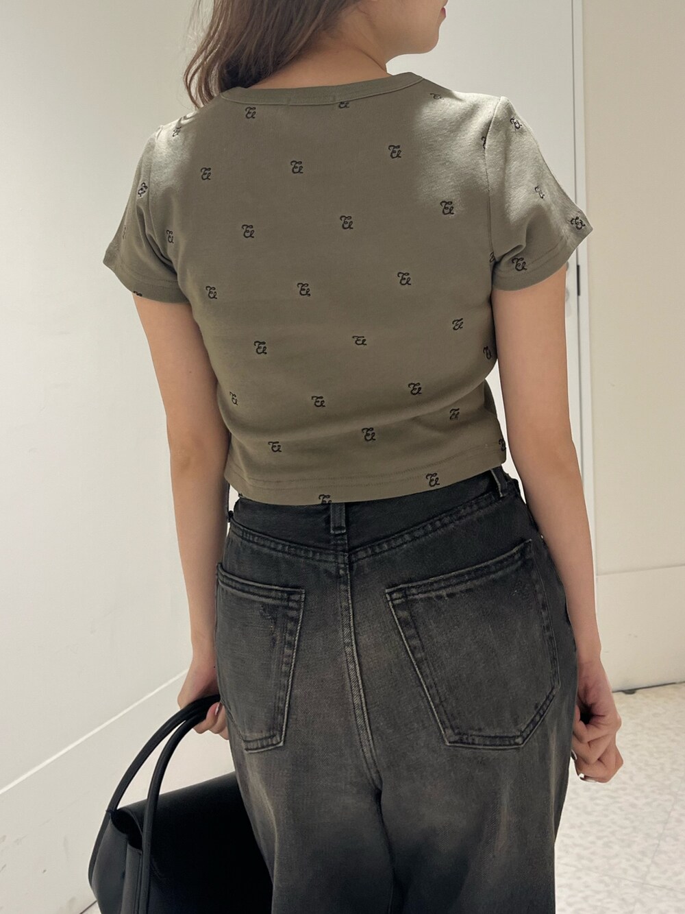 グリーン系のTシャツ/カットソー、ブラック系のブーツ、ブラック系のハンドバッグを着用したレディースの春コーディネートの6枚目の写真