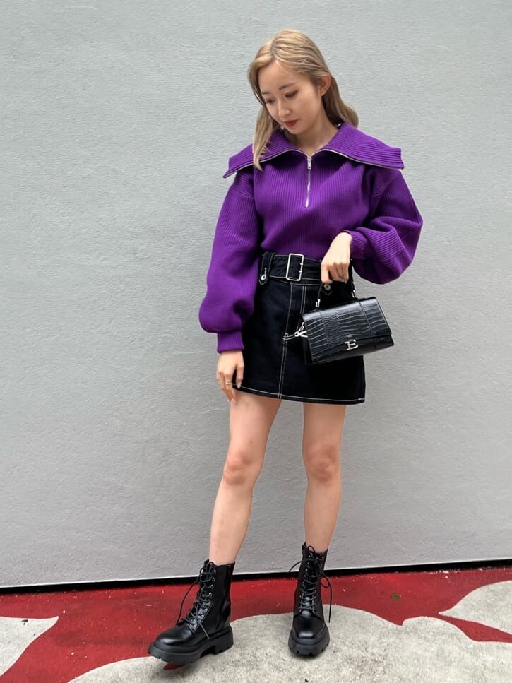 ブラック系のブーツ、ブラック系のデニムスカート、パープル系のニット/セーターを着用したレディースの秋コーディネートの2枚目の写真