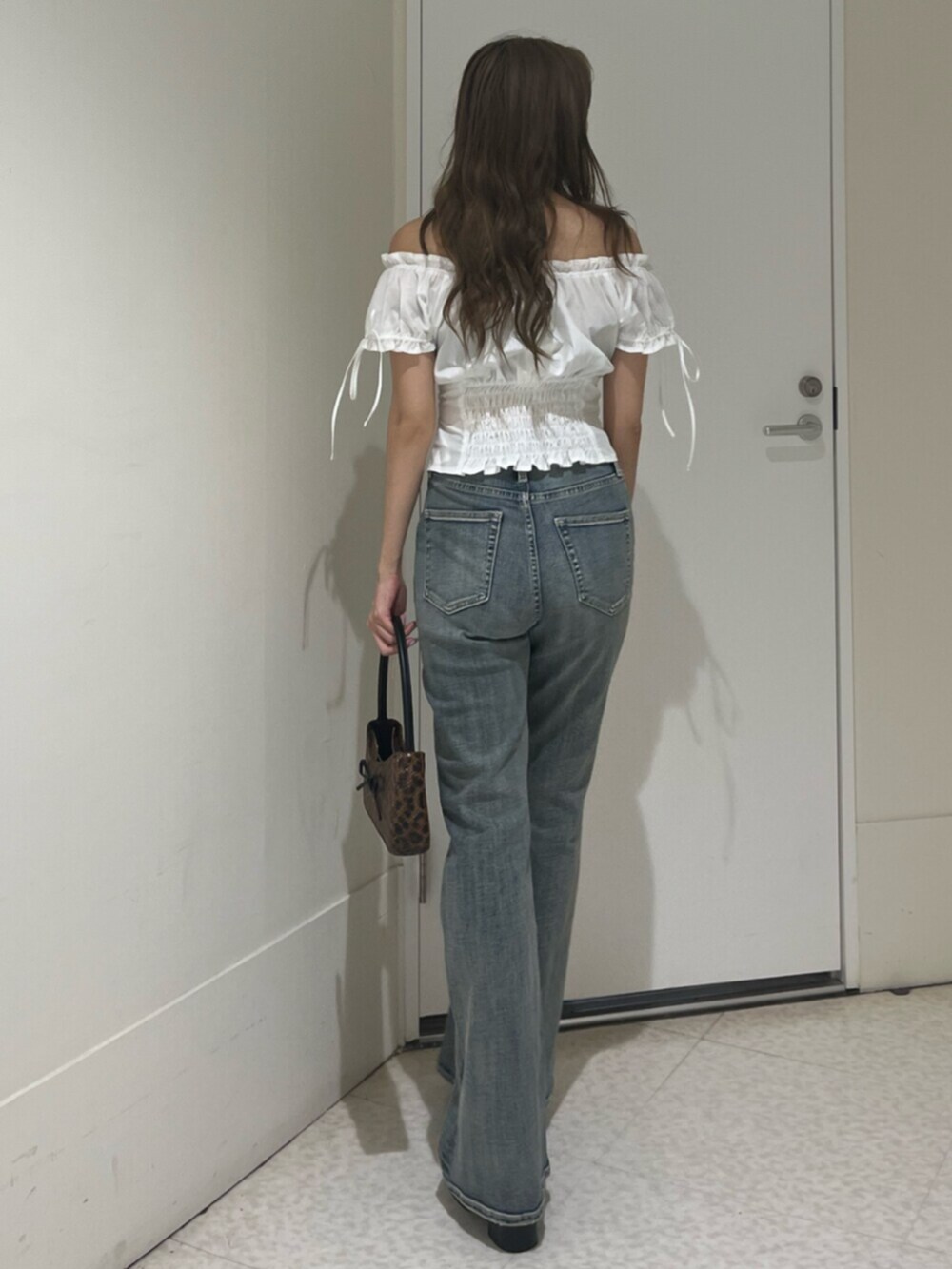 ブラウン系のハンドバッグ、ブラック系のサンダル、ホワイト系のシャツ/ブラウスを着用したレディースの夏コーディネートの3枚目の写真