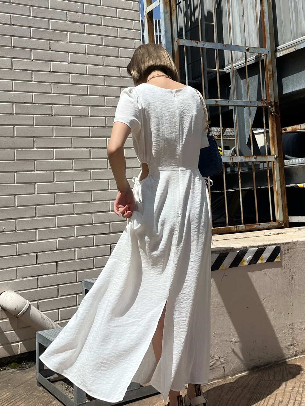 ホワイト系のワンピース、ベージュ系のサンダル、ブルー系のショルダーバッグを着用したレディースの春コーディネートの9枚目の写真