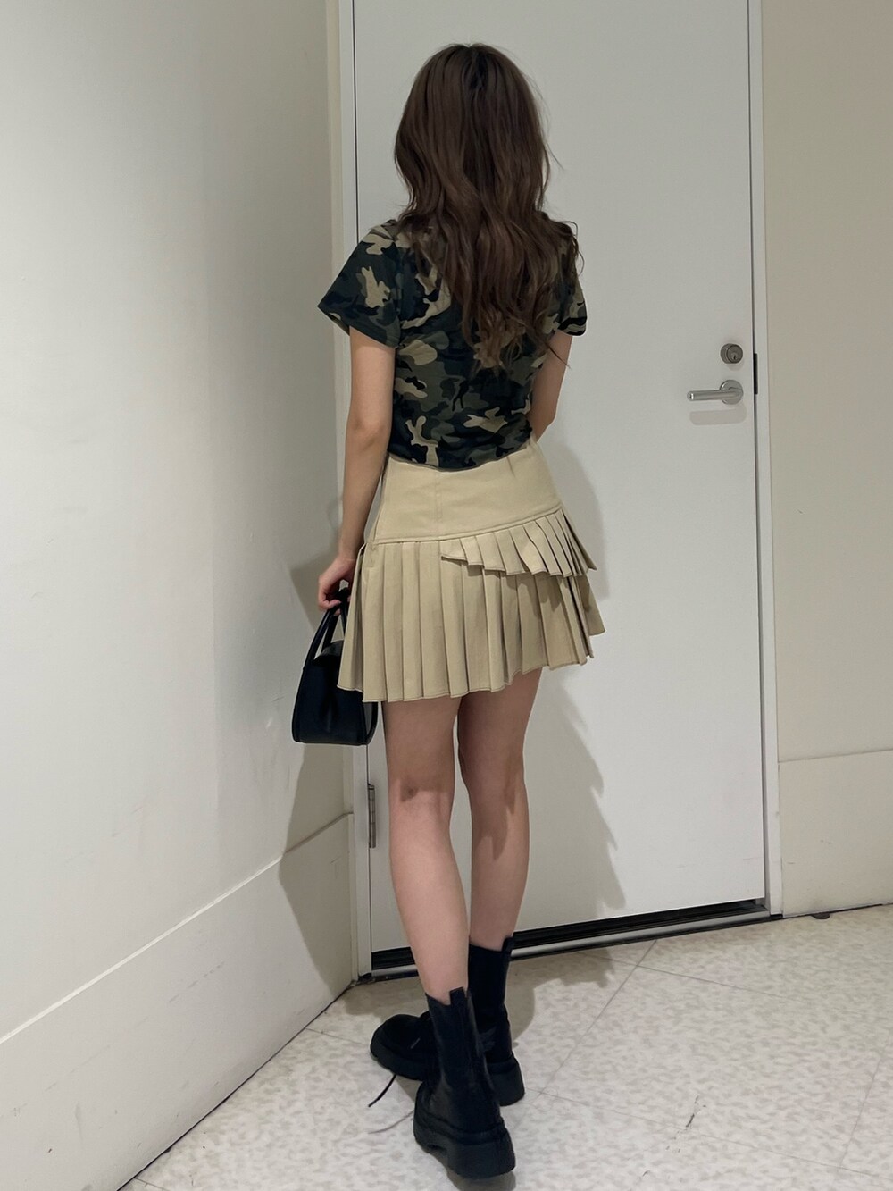 グリーン系のTシャツ/カットソー、ブラック系のブーツ、ベージュ系のスカートを着用したレディースの春コーディネートの3枚目の写真