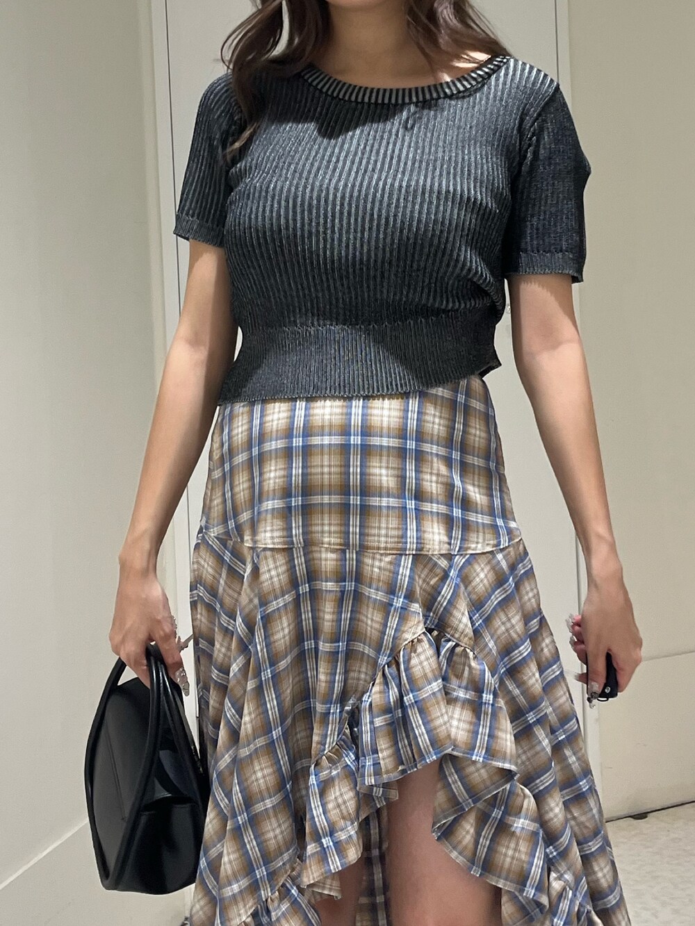 ベージュ系のスカート、ブラック系のハンドバッグ、ブラック系のサンダルを着用したレディースの夏コーディネートの4枚目の写真