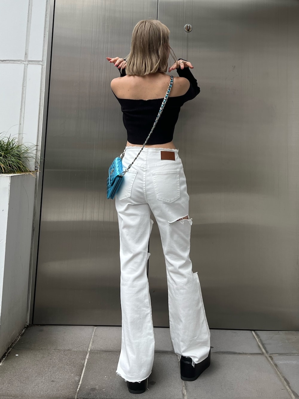 グリーン系のニット/セーター、ブラック系のデニムパンツ、ブラック系のショルダーバッグを着用したレディースの春コーディネートの3枚目の写真