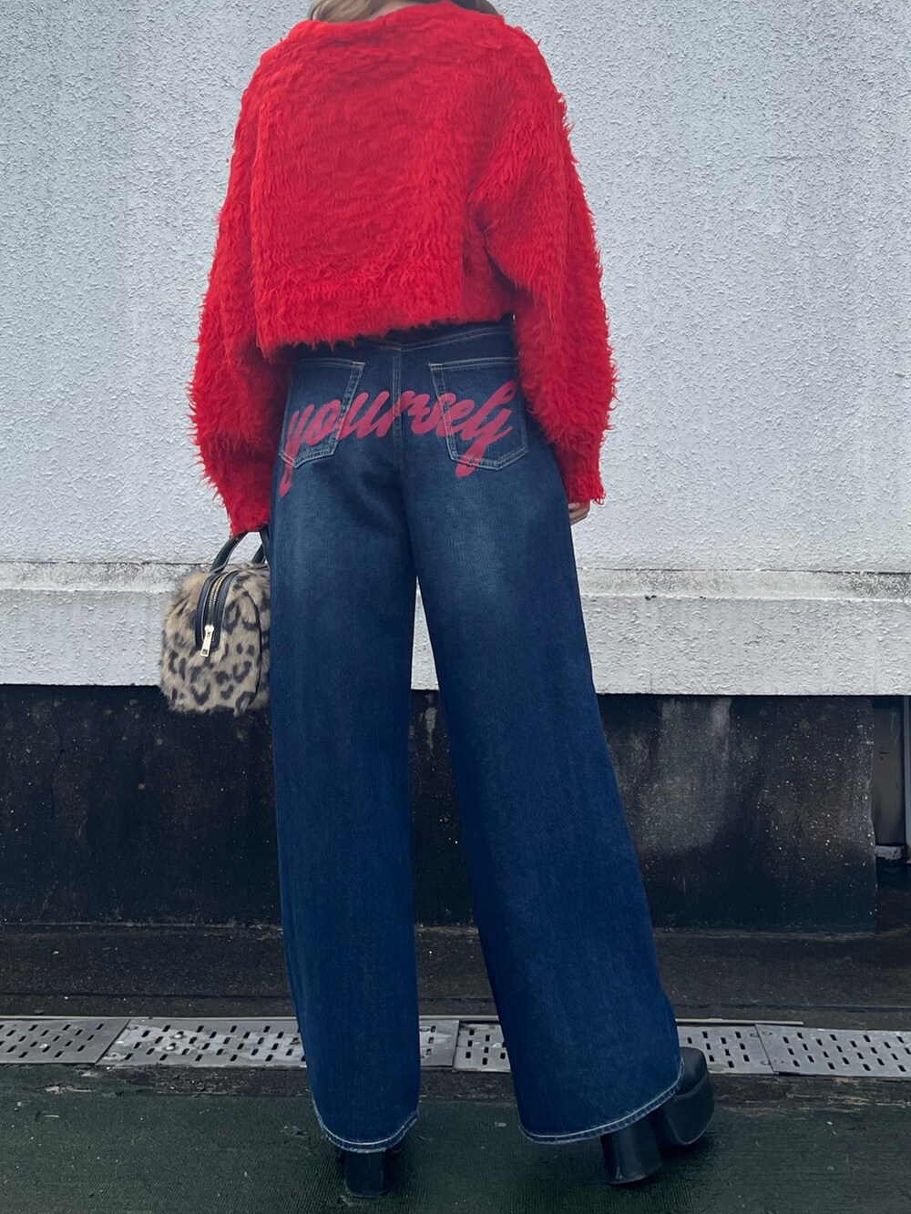 ブラック系のブーツ、レッド系のニット/セーター、ブルー系のデニムパンツを着用したレディースの冬コーディネートの3枚目の写真