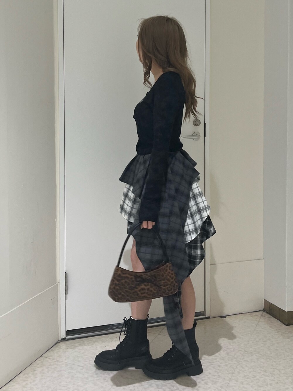 ブラウン系のハンドバッグ、ブラック系のブーツ、ブラック系のTシャツ/カットソーを着用したレディースの春コーディネートの2枚目の写真