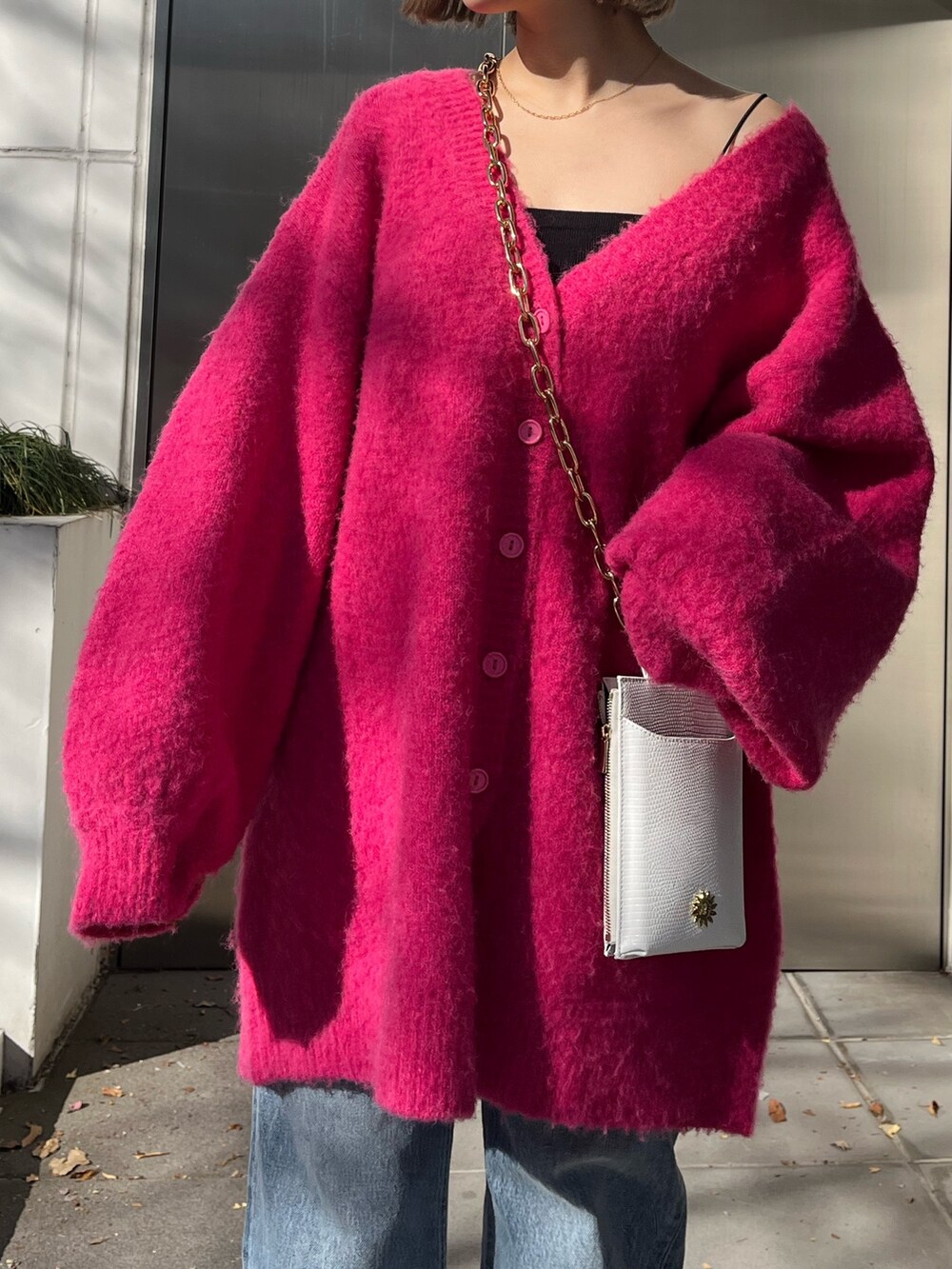 ブルー系のデニムパンツ、ホワイト系のショルダーバッグ、ピンク系のカーディガン/ボレロを着用したレディースの冬コーディネートの3枚目の写真