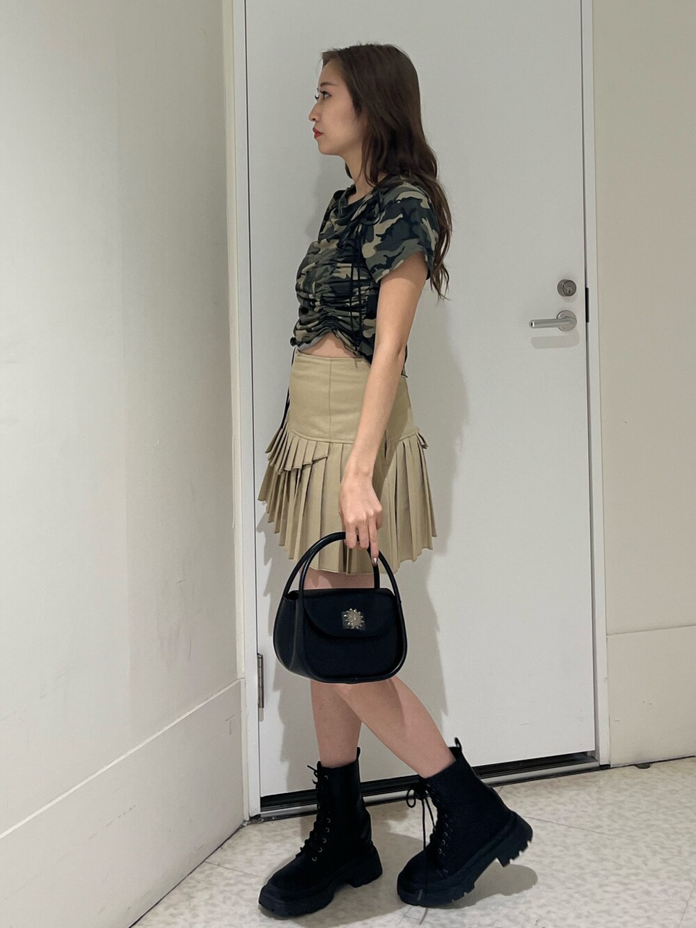 グリーン系のTシャツ/カットソー、ブラック系のブーツ、ベージュ系のスカートを着用したレディースの春コーディネートの2枚目の写真