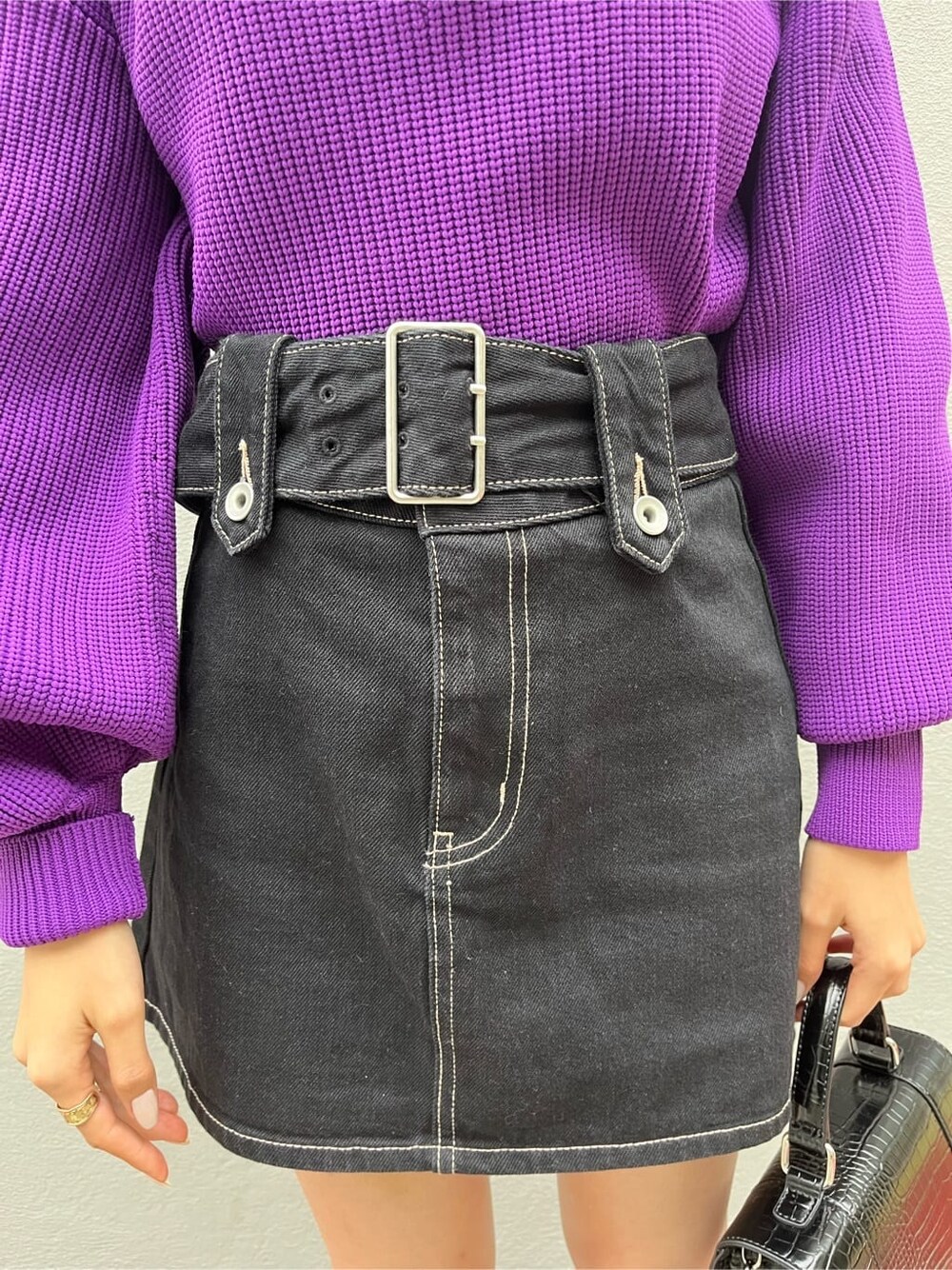 ブラック系のブーツ、ブラック系のデニムスカート、パープル系のニット/セーターを着用したレディースの秋コーディネートの6枚目の写真